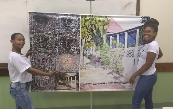 Duas pessoas posam junto a um painel com imagens impressas.