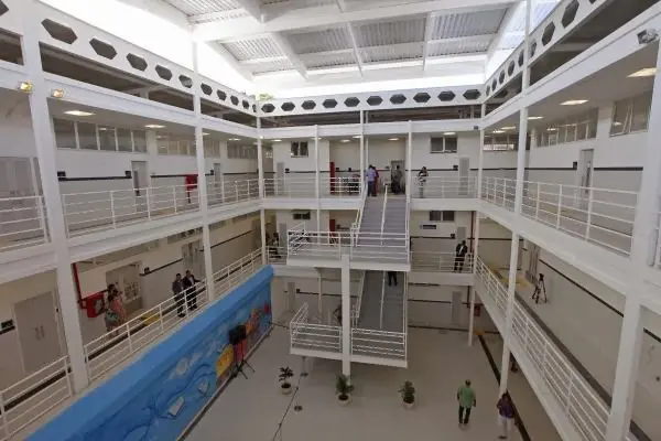 Corredor interno de escola com pessoas caminhando.