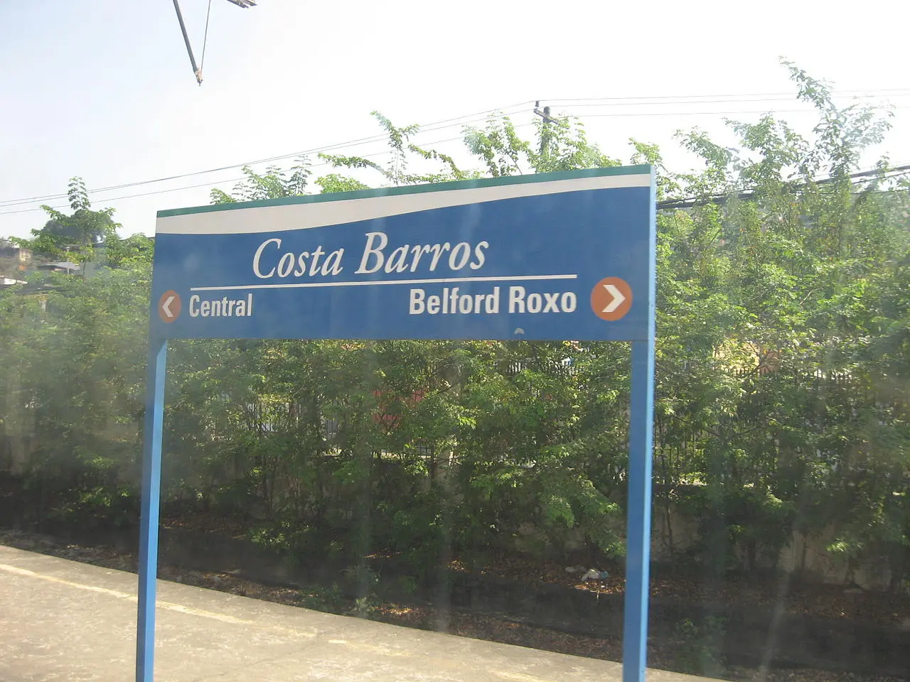 Sinal de direção azul em área verde, Costa Barros, Central e Belford Roxo.