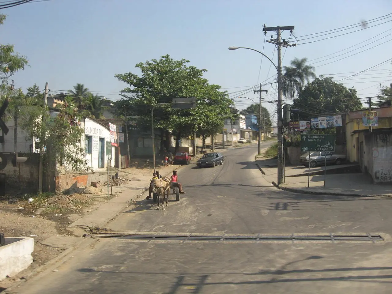 Rua urbana com construções e vegetação.