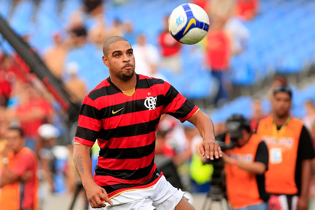 Jogador de futebol em ação em estádio com torcedores ao fundo.