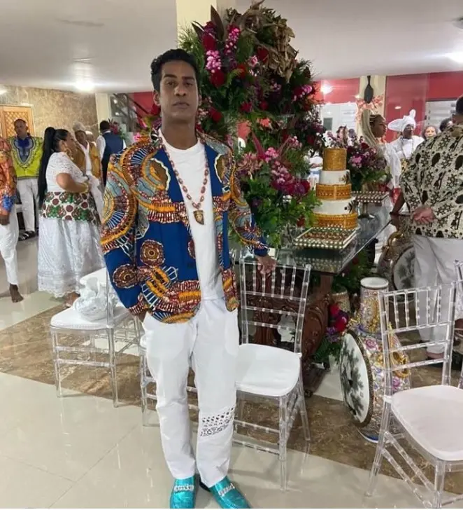 Fotografia de evento festivo com homem em trajes tradicionais e mesa com bolo adornado.