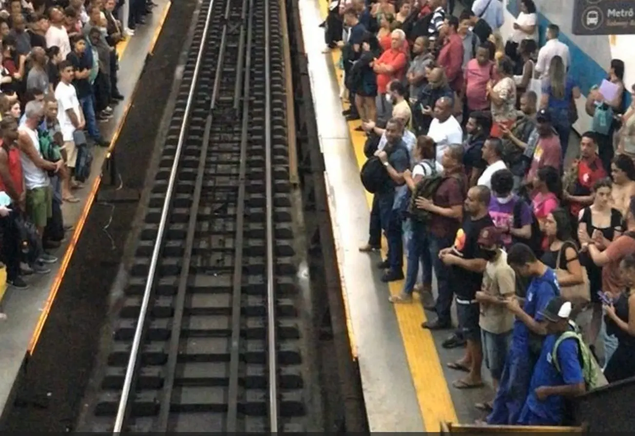 Estação de metrô com plataforma lotada e sinal "Metro".