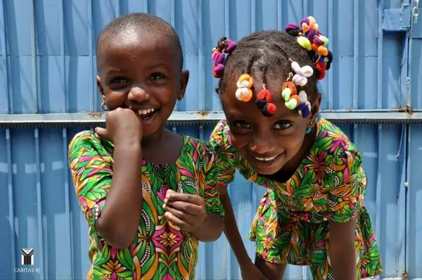 Duas crianças sorridentes em frente a um fundo azul metálico.