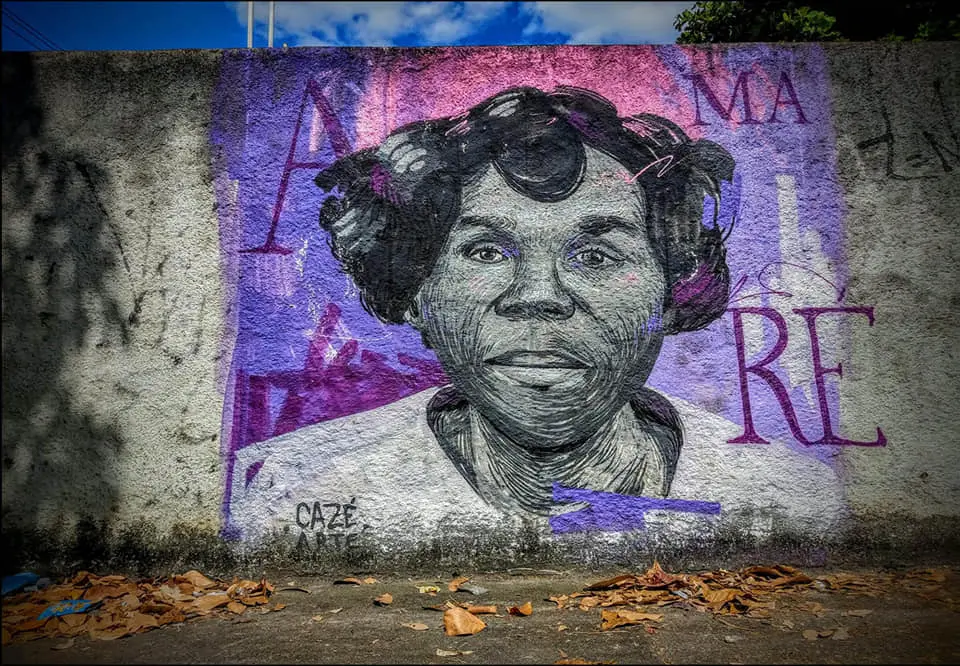 Pintura mural de mulher com coque, letras coloridas ao fundo.