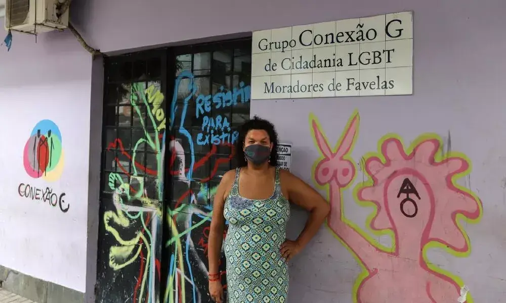 Pessoal com máscara em frente a parede com grafite e logotipo "Conexão".