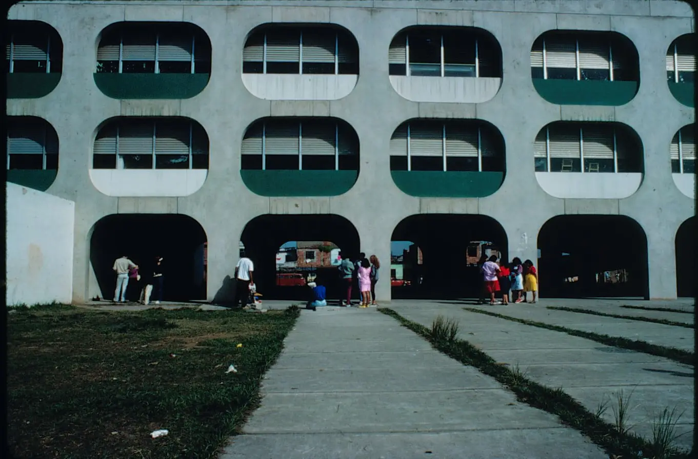 Edifício moderno com janelas retangulares e pessoas caminhando.