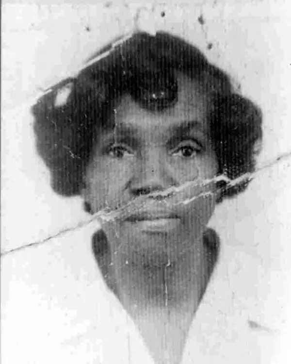 Mulher sorridente em uniforme de enfermeira, retrato preto e branco.