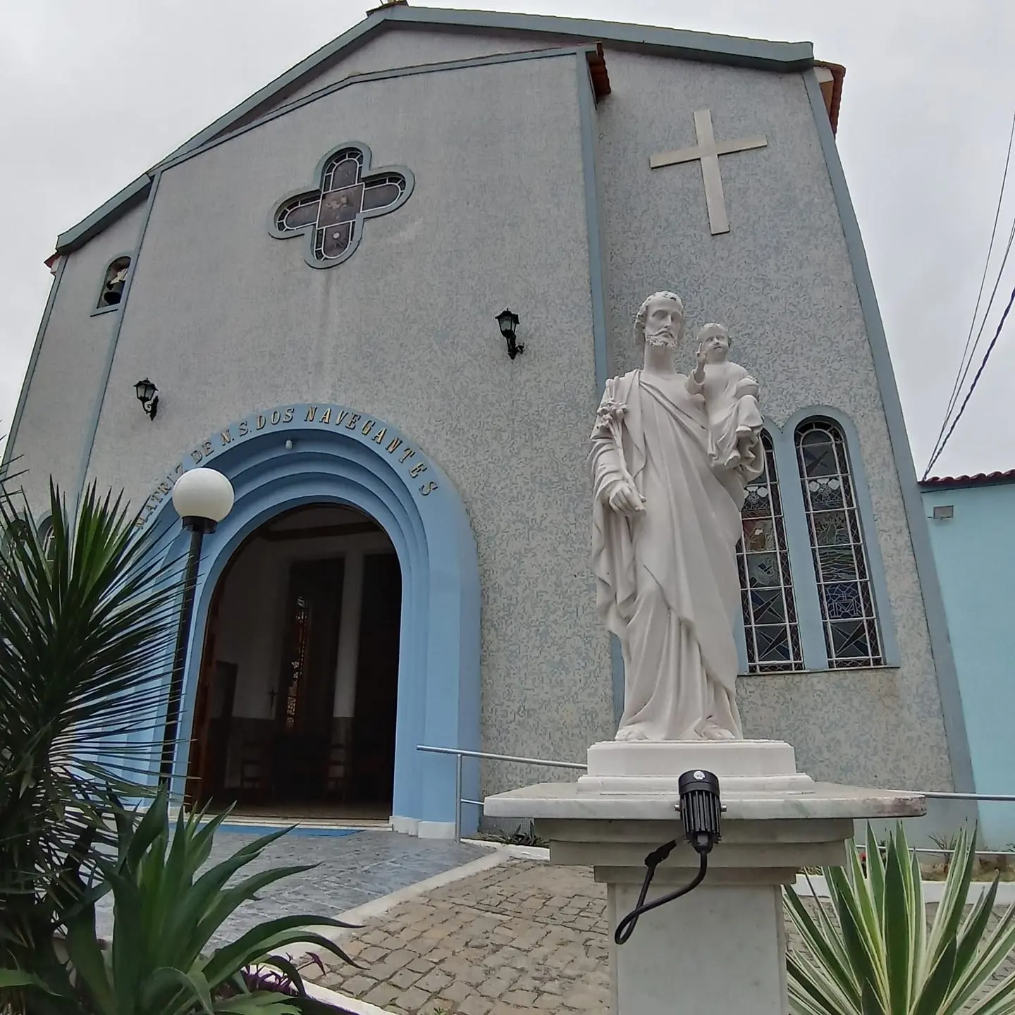 Edifício religioso com estátuas e cruz na fachada.