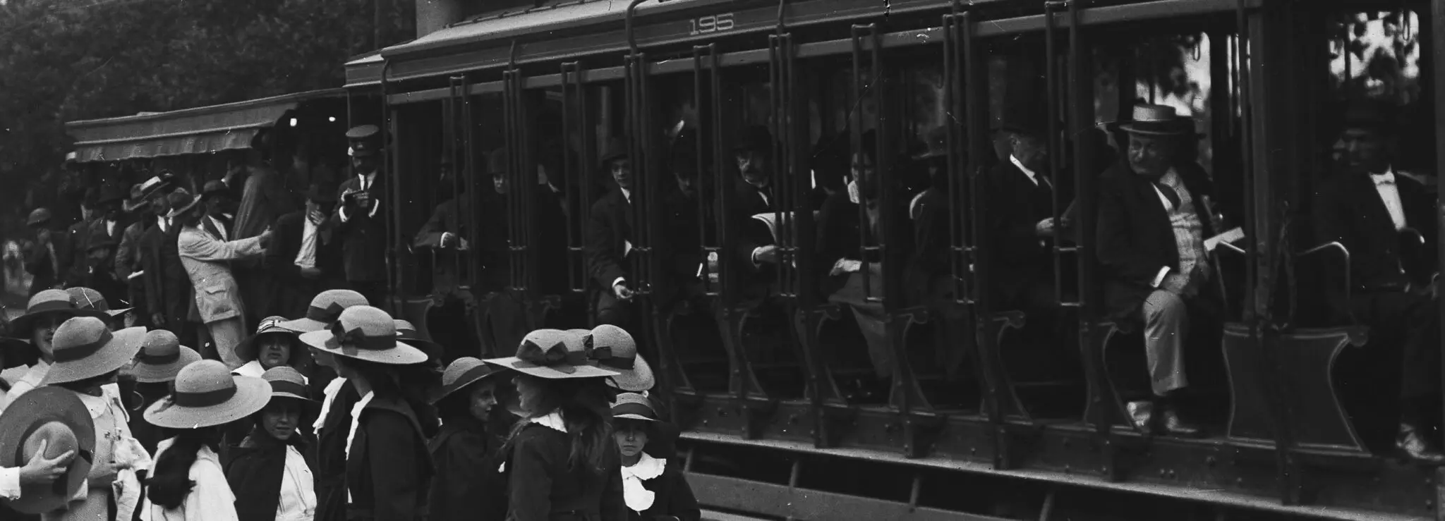 Crianças em trajes formais perto de um trem metálico.