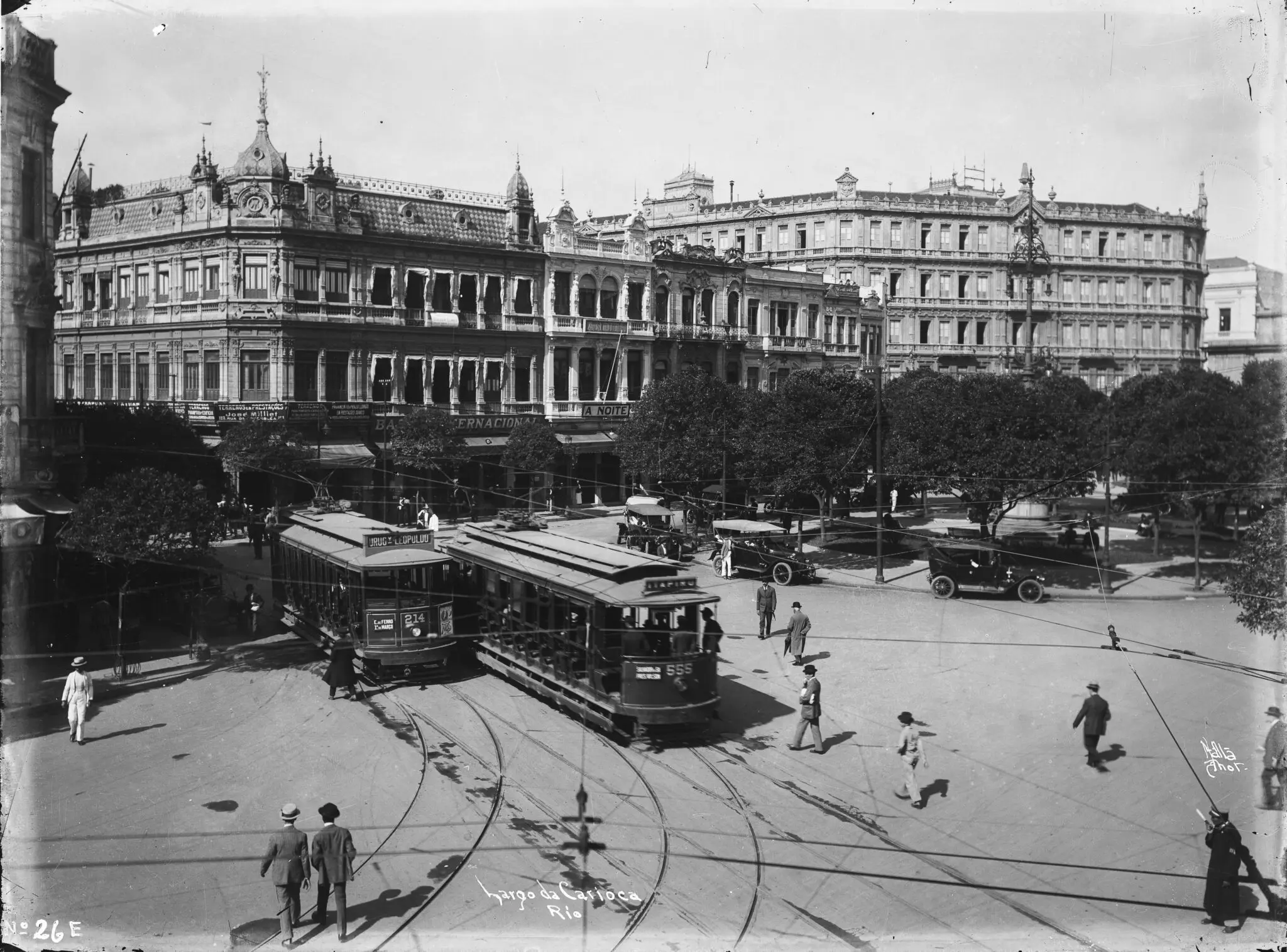 Praça histórica com bondes e edifícios ornamentados.