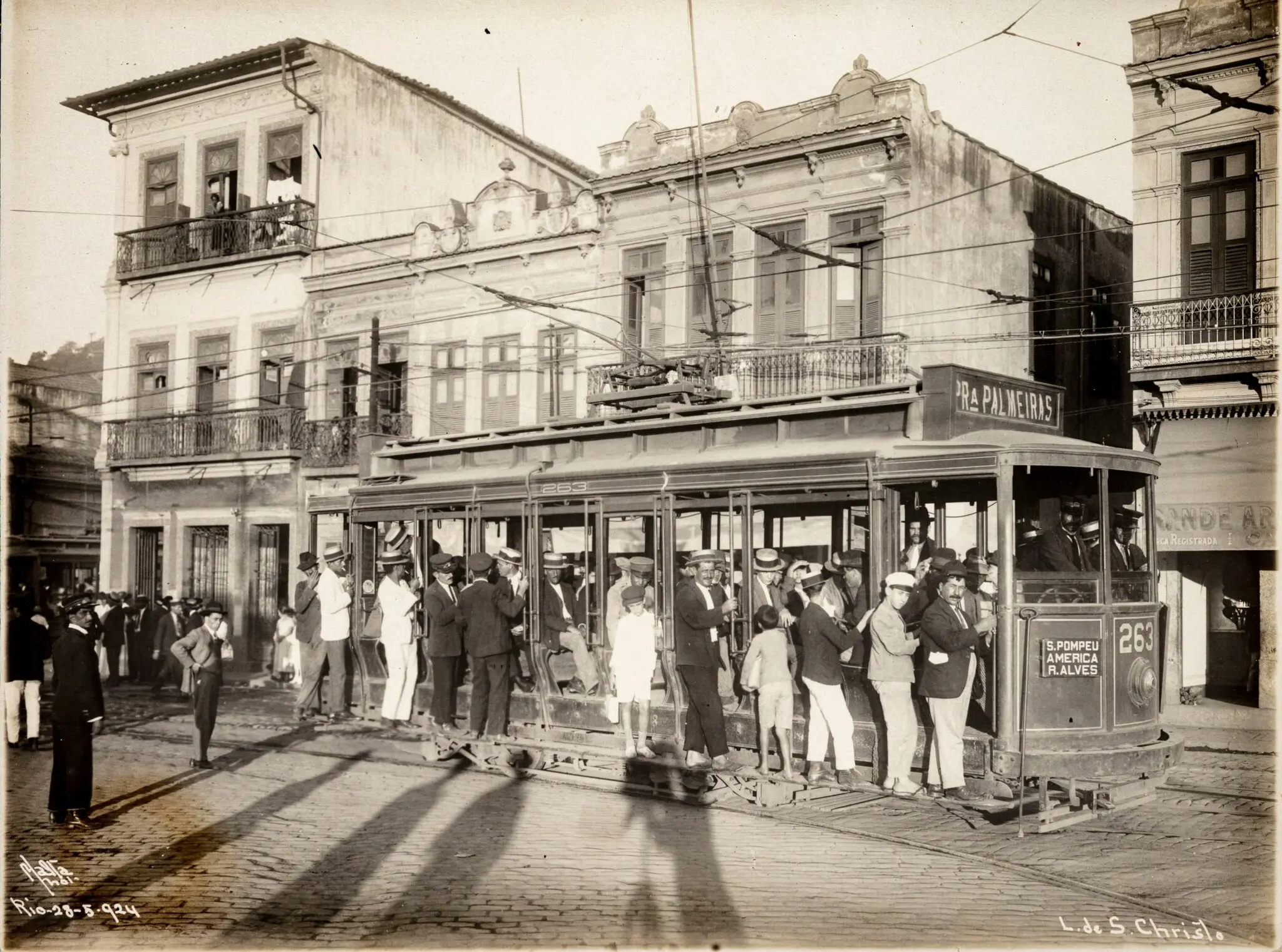 Bondinho lotado em praça histórica, com pessoas vestindo roupas típicas.