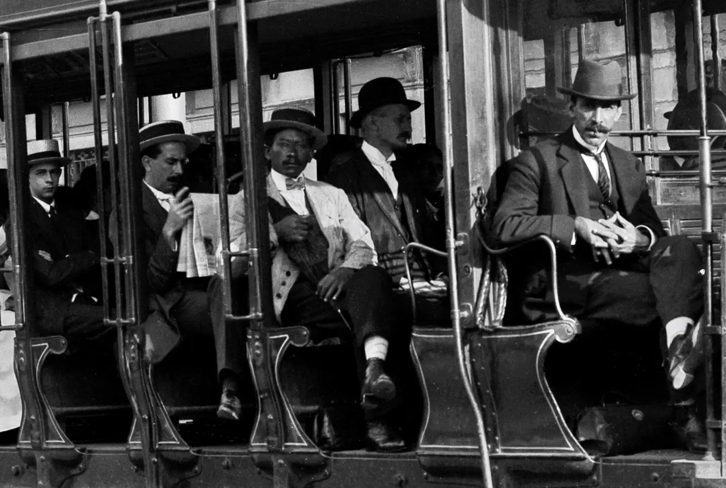 Homens em ternos e chapéus em ônibus, preto e branco.