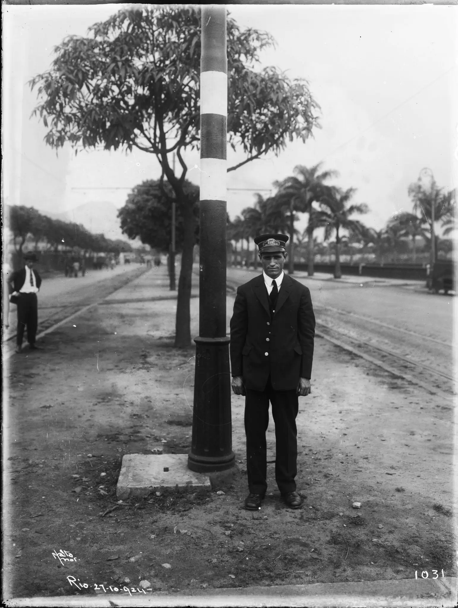 Homem militar ao lado de coluna de iluminação pública em preto e branco.