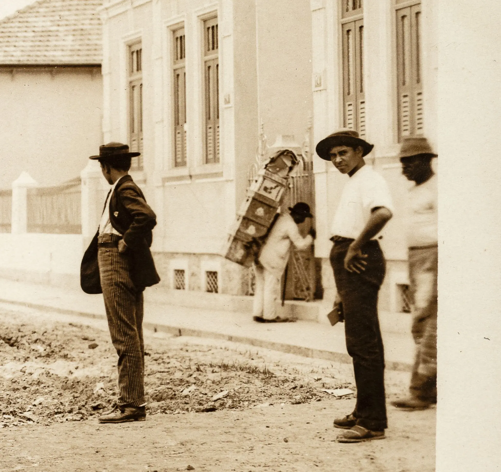 Três homens em uma rua em tons de sepia.