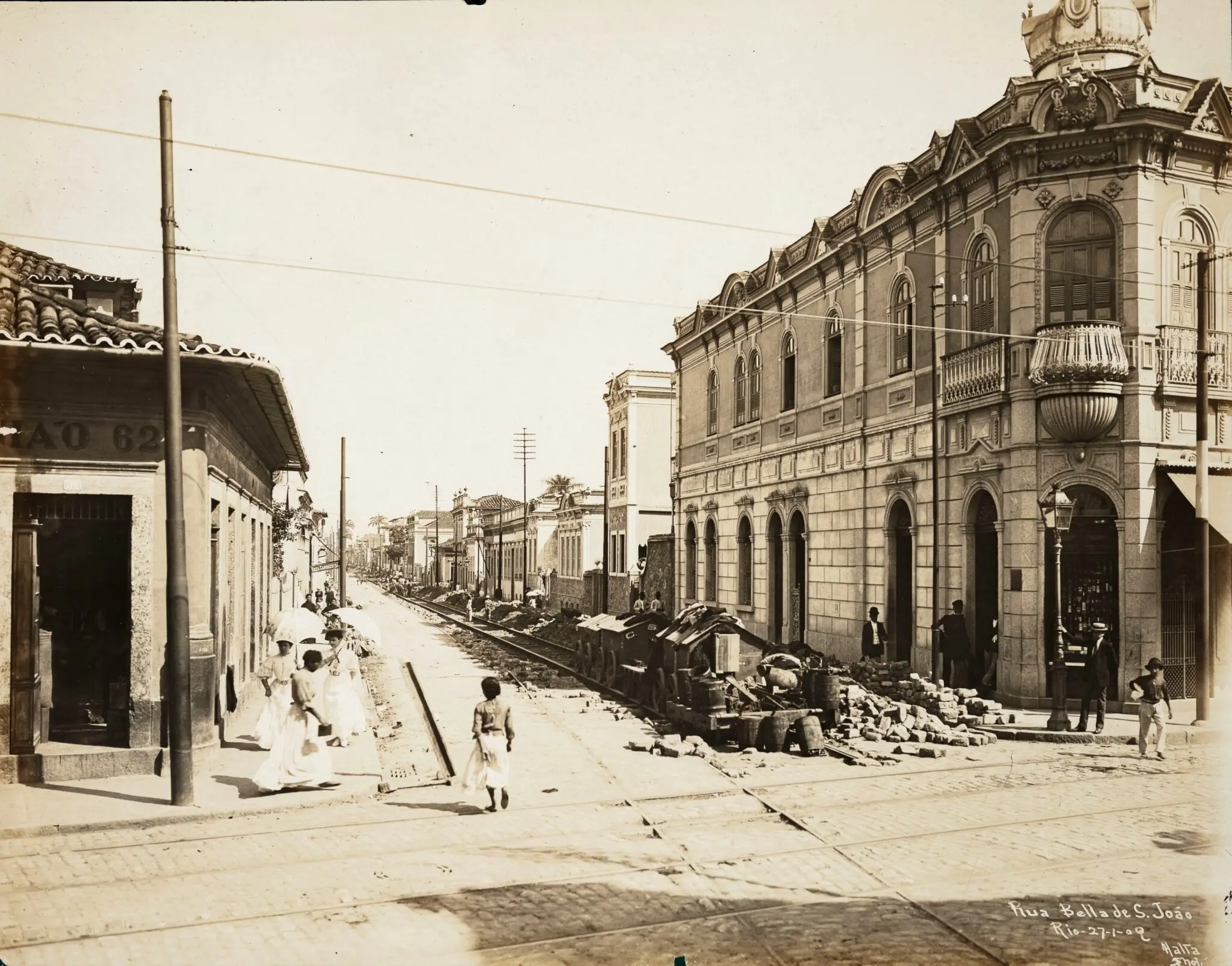 Fotografia antiga de rua urbana com edifícios e linha férrea.