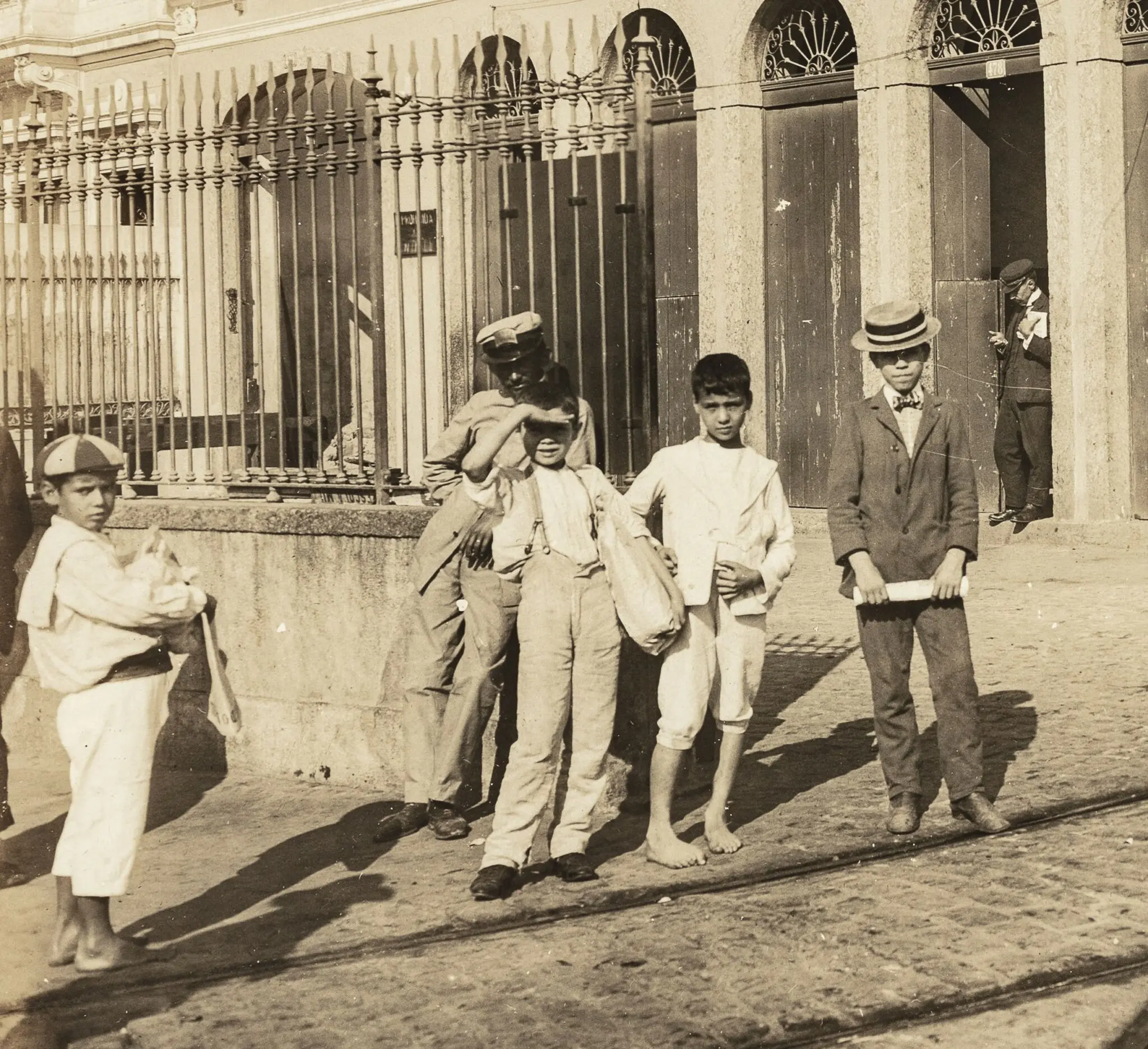 Crianças em frente a um edifício com grades metálicas.
