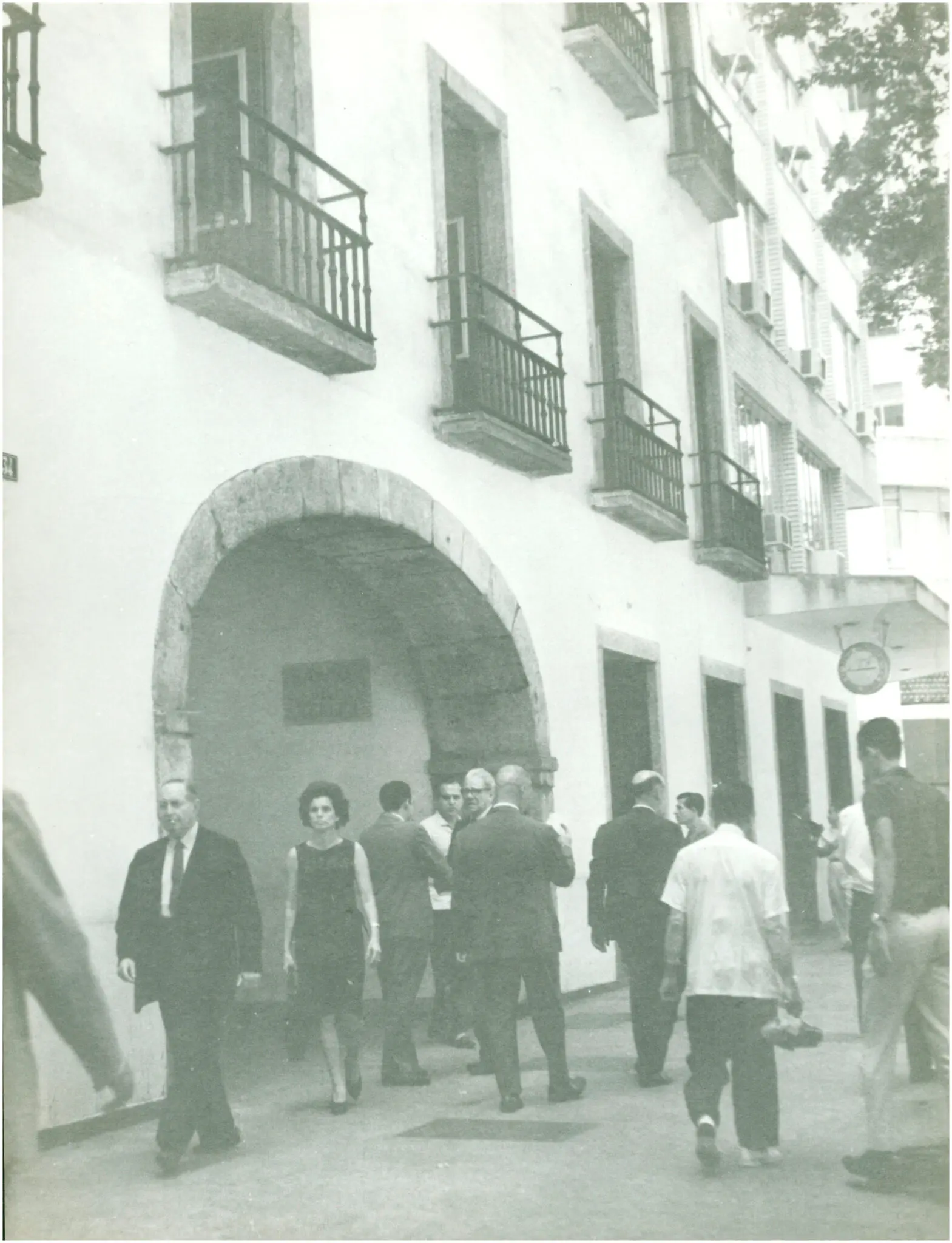 Grupo de pessoas caminhando em frente a edifício tradicional.