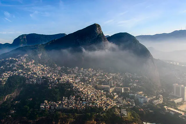 Cidade montanhosa com edifícios e montanhas cobertas de neblina.