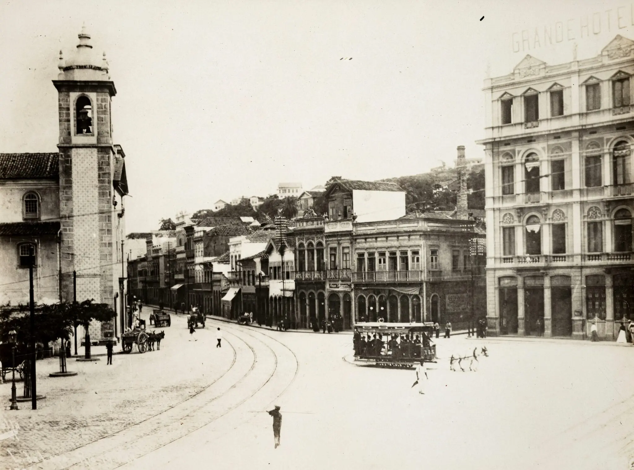 Praça histórica com bonde, edifícios e hotel.