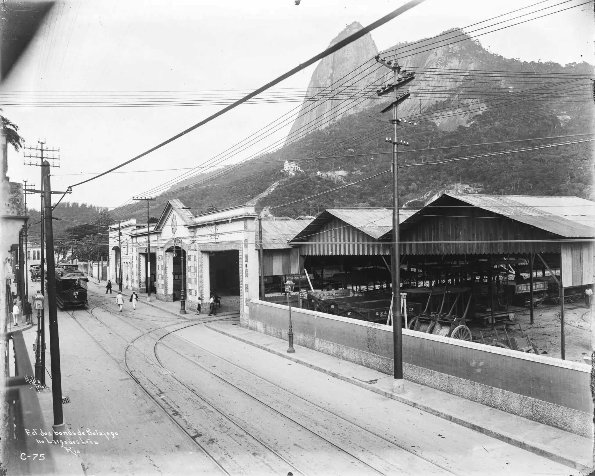 Fotografia histórica em preto e branco de uma rua com bondes e edifícios.