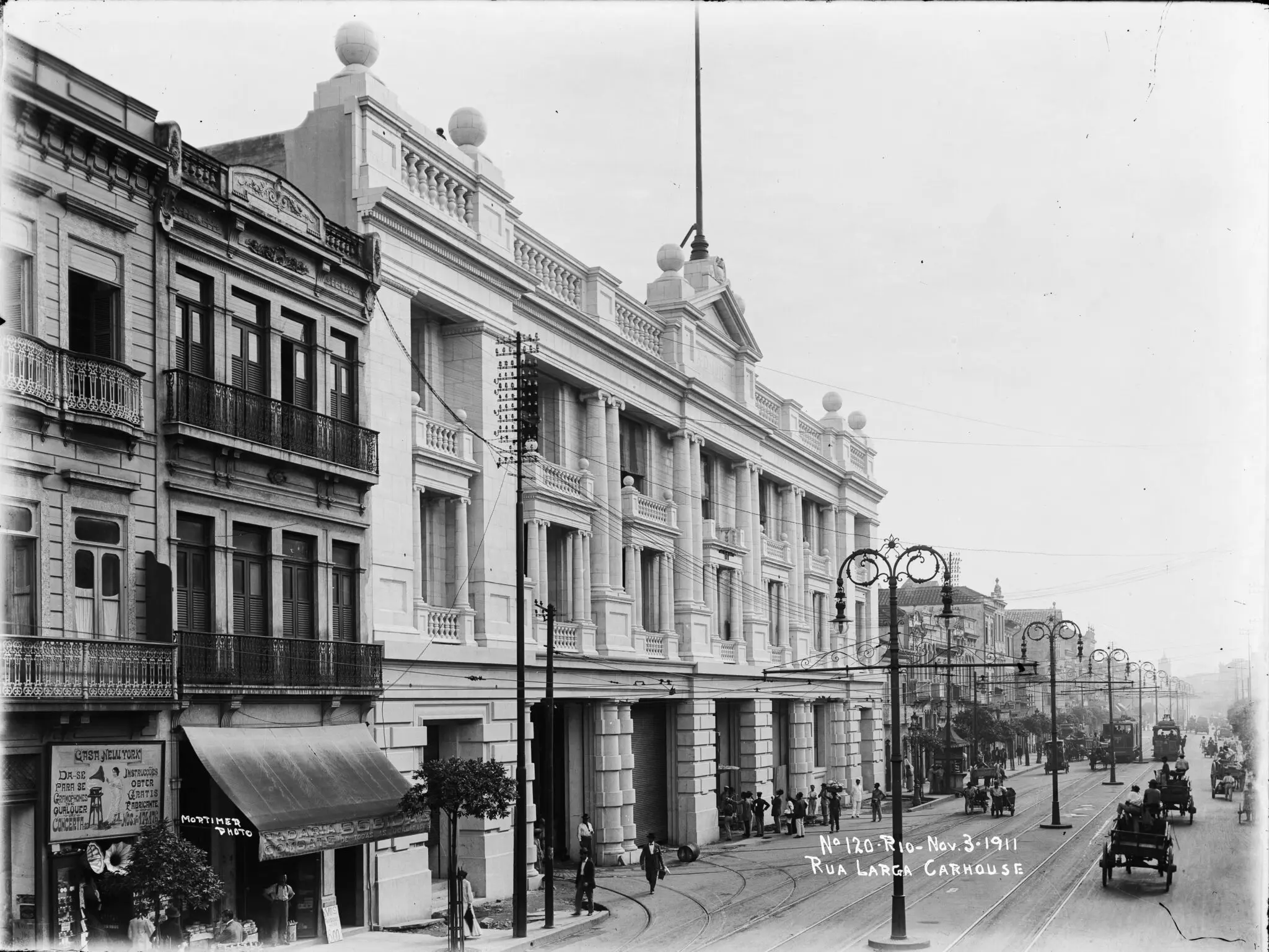 Imagem histórica de rua urbana com edifícios clássicos e movimento.