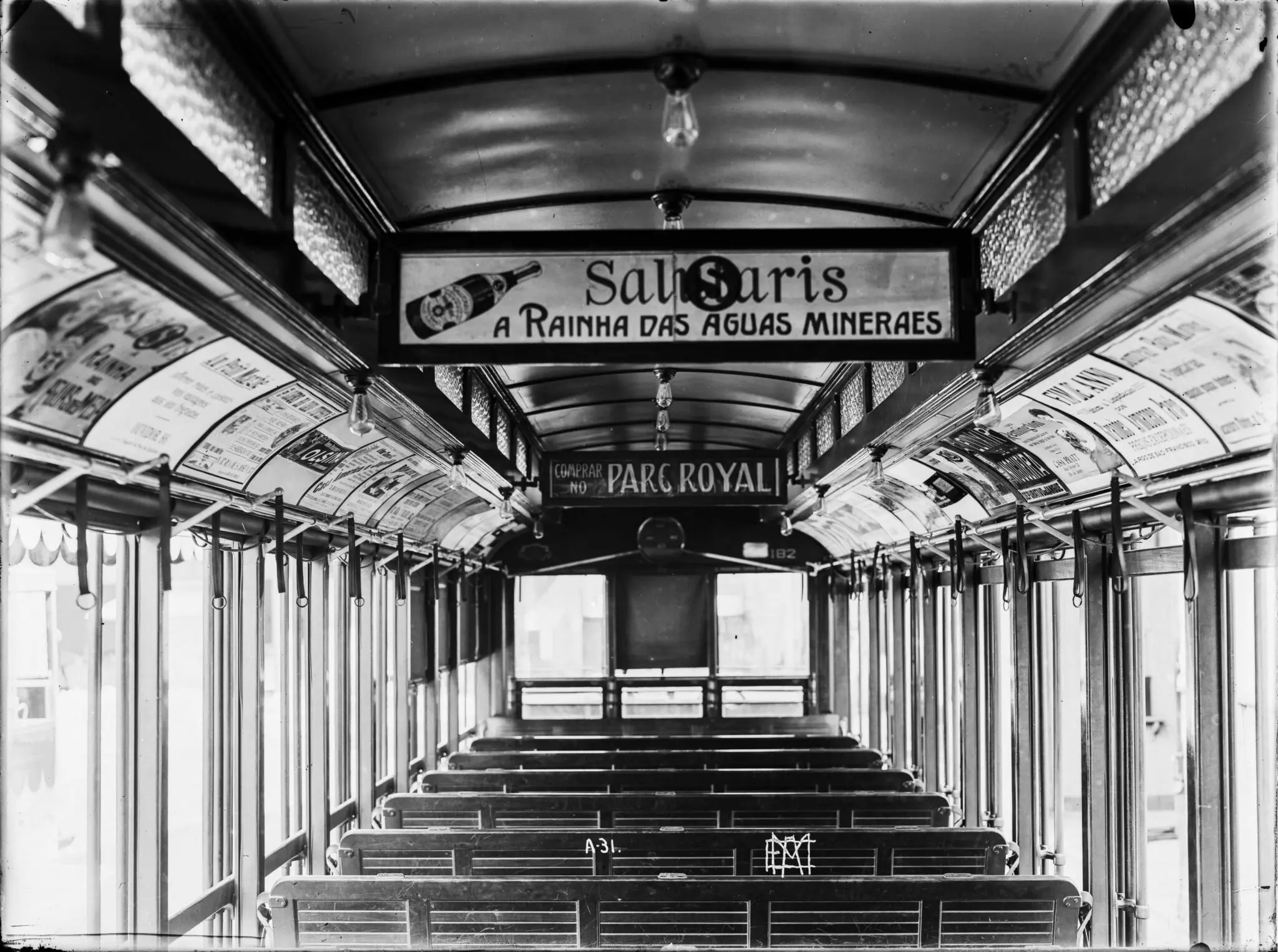 Interior de bondes antigos com bancos vazios e anúncios publicitários.