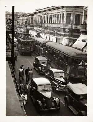 Engarrafamento urbano com ônibus e carros antigos.