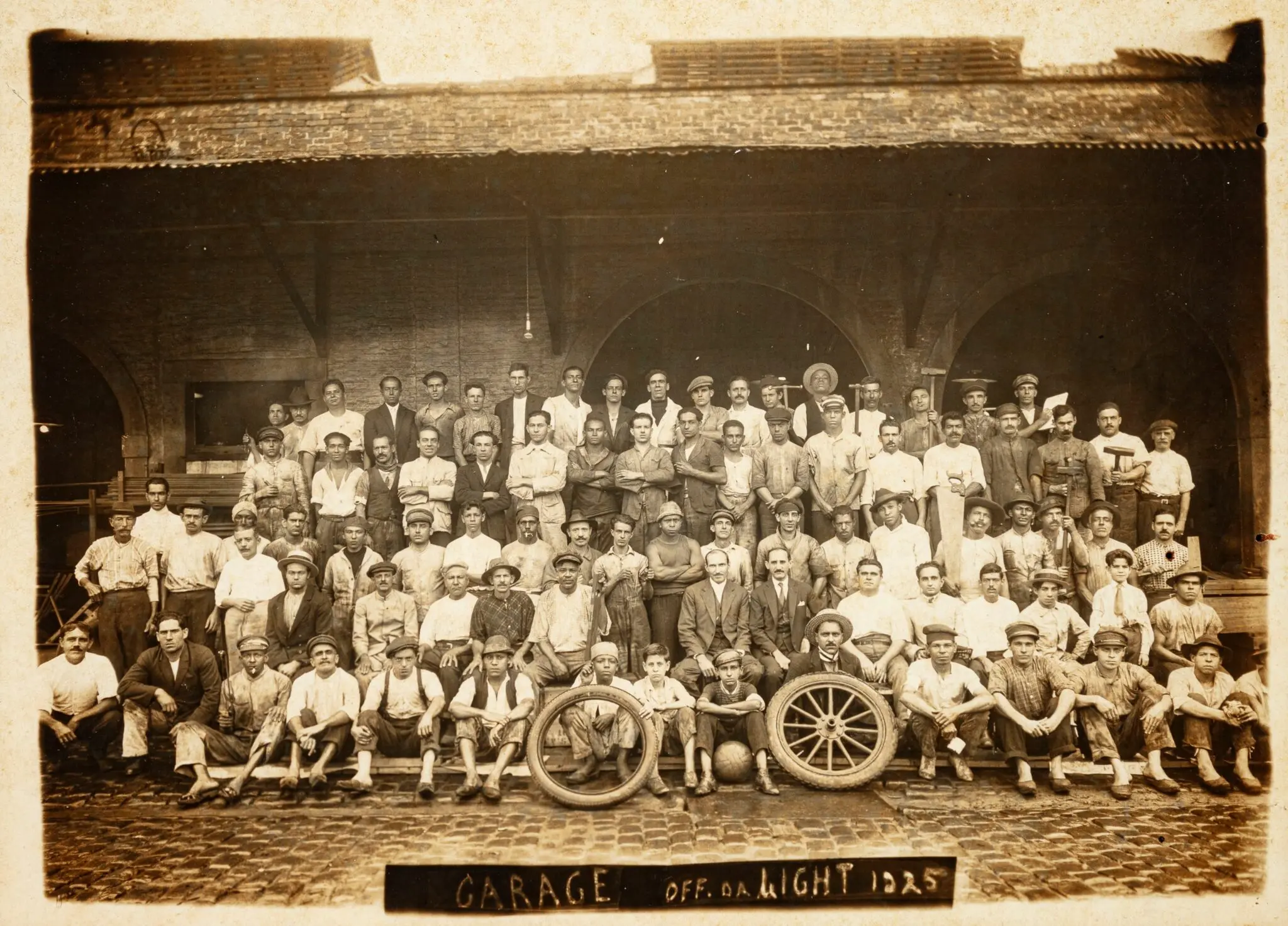 Trabalhadores adultos e crianças em frente a construção industrial, 1925.