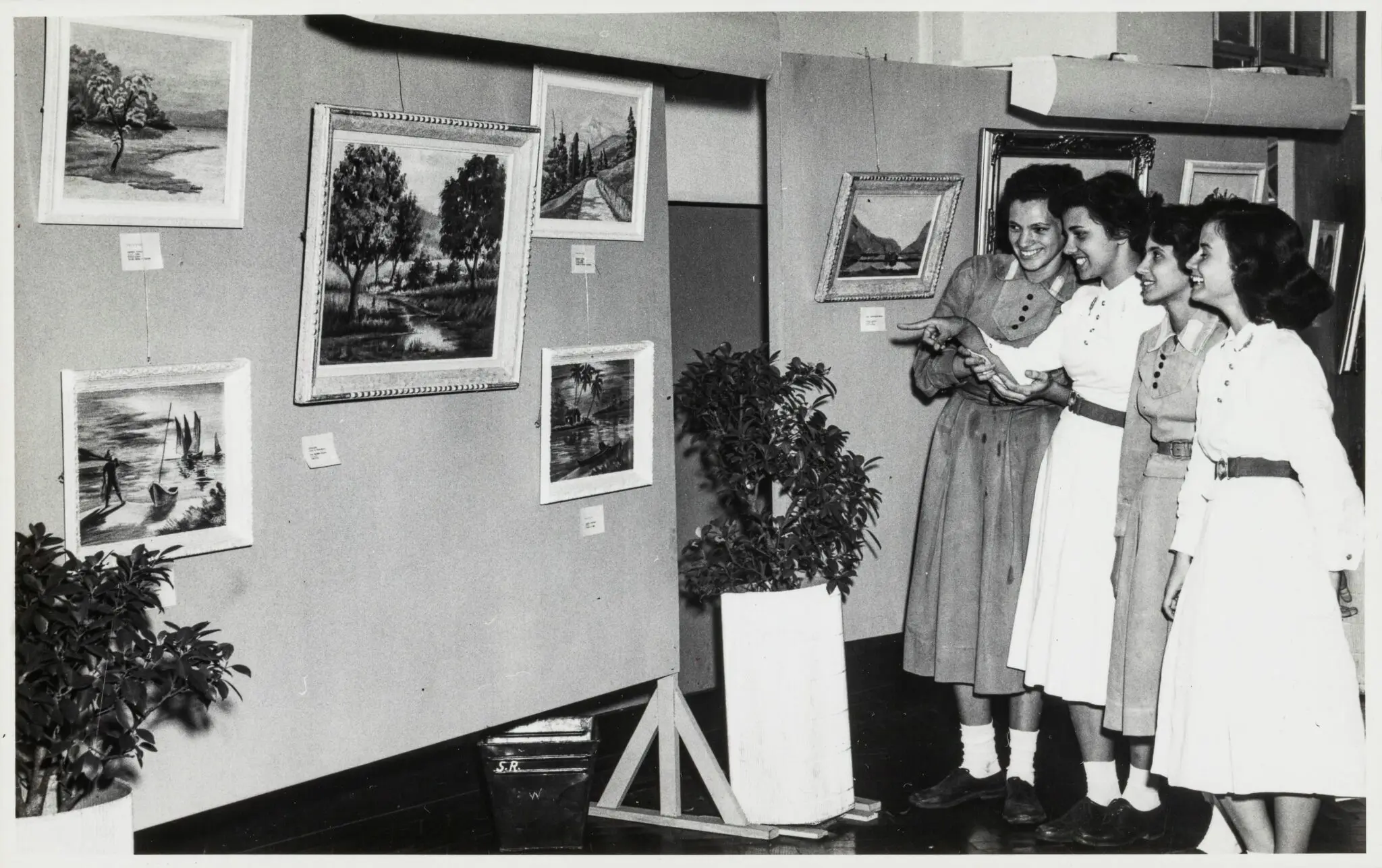 Exposição de arte com mulheres conversando.
