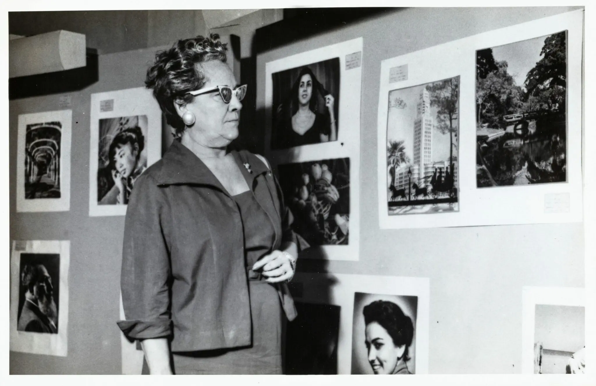 Exposição de arte com retratos e paisagens urbanas em preto e branco.