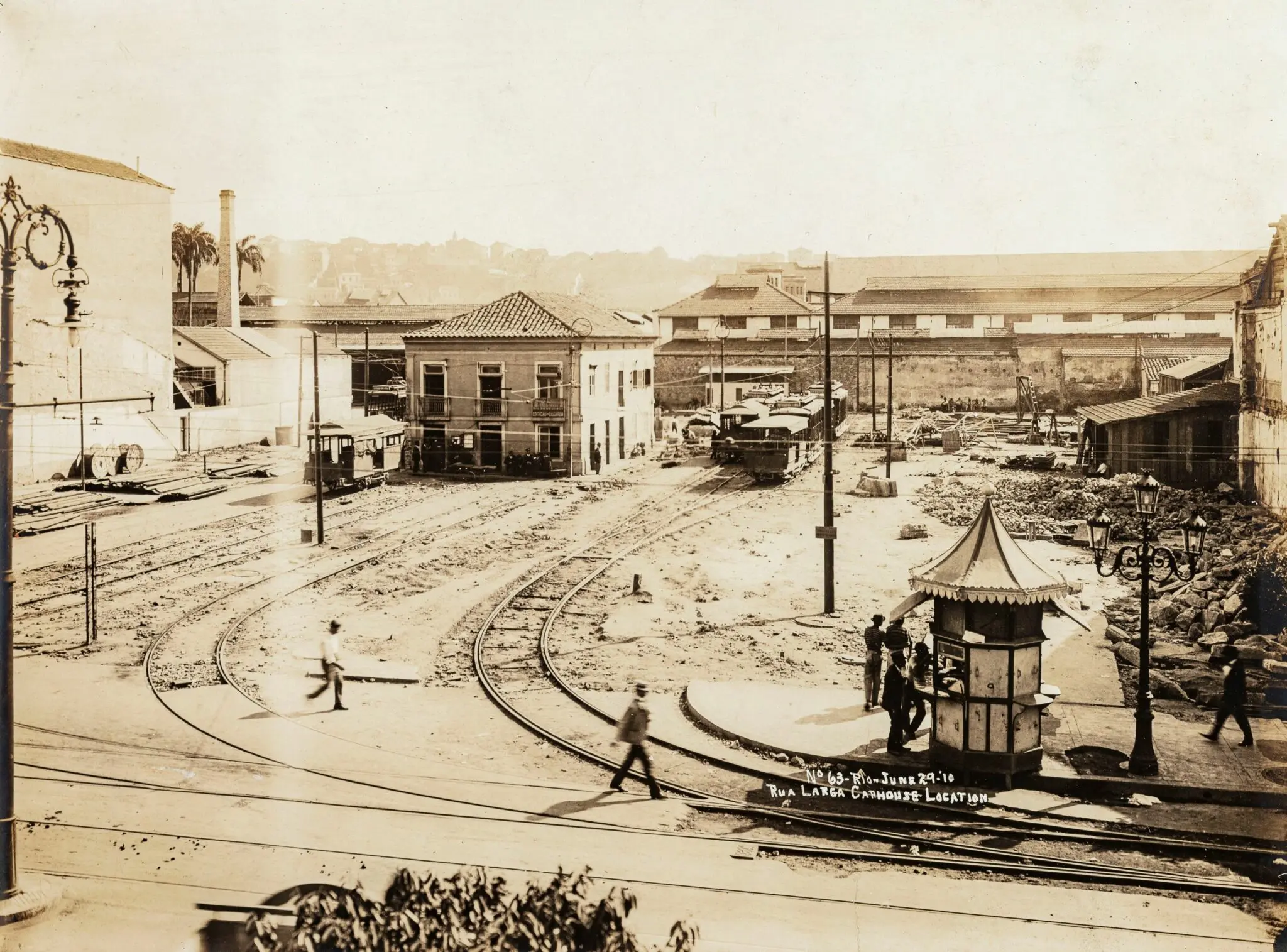 Uma foto histórica em preto e branco de uma cidade com trilhos de bondes e edifícios.