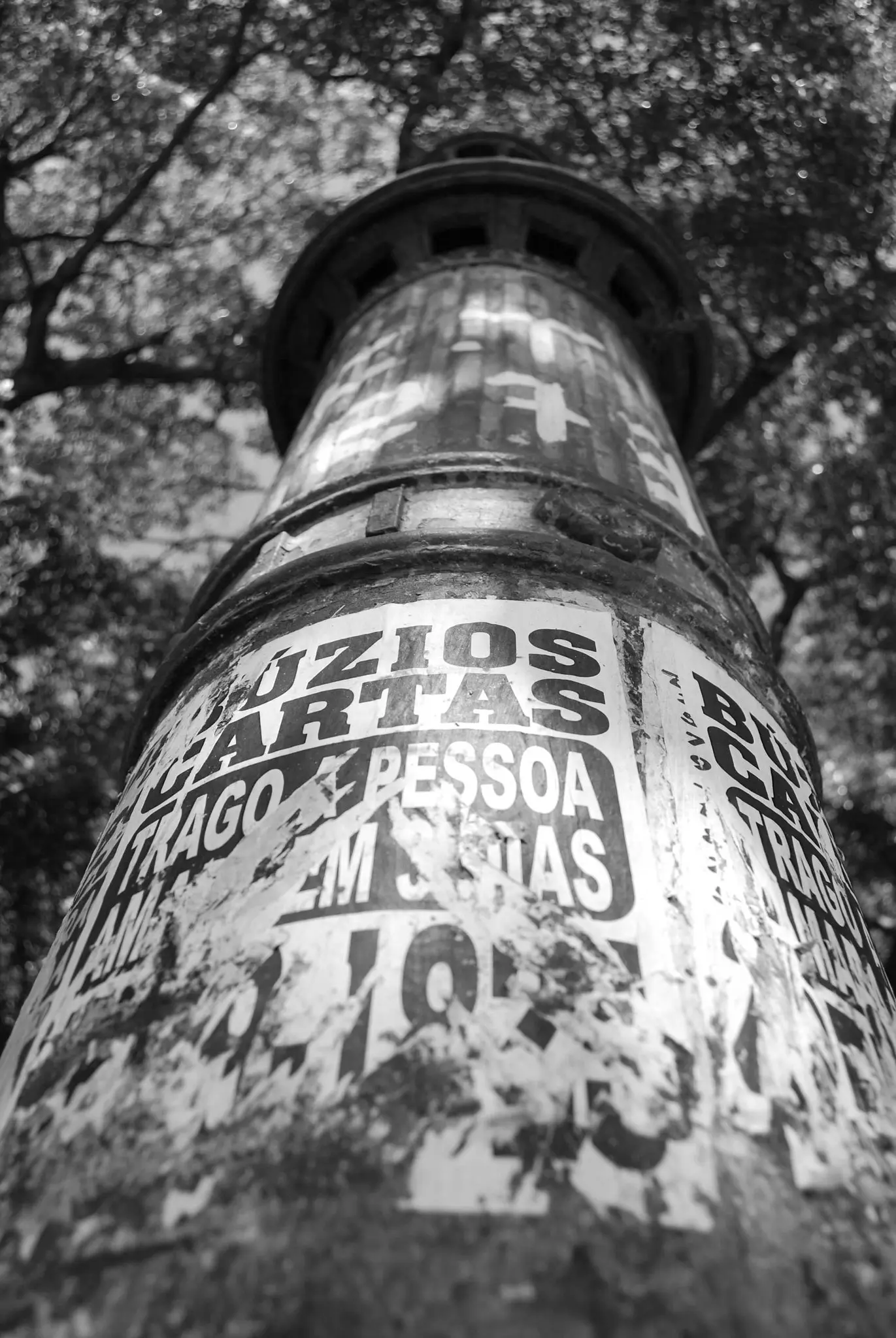 Poste com adesivos e texto danificado em Búzios.