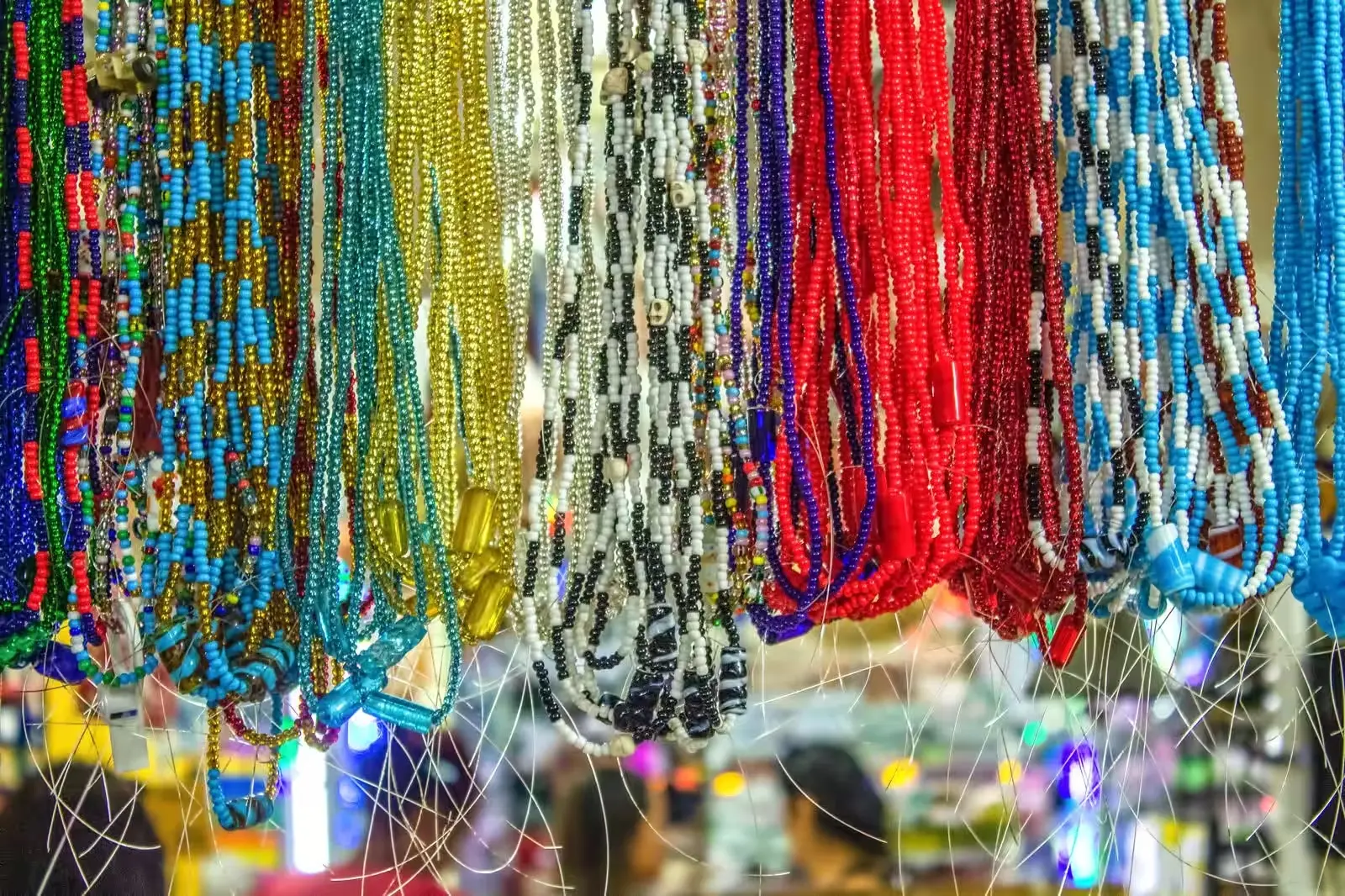 Mercado com colares coloridos pendurados.