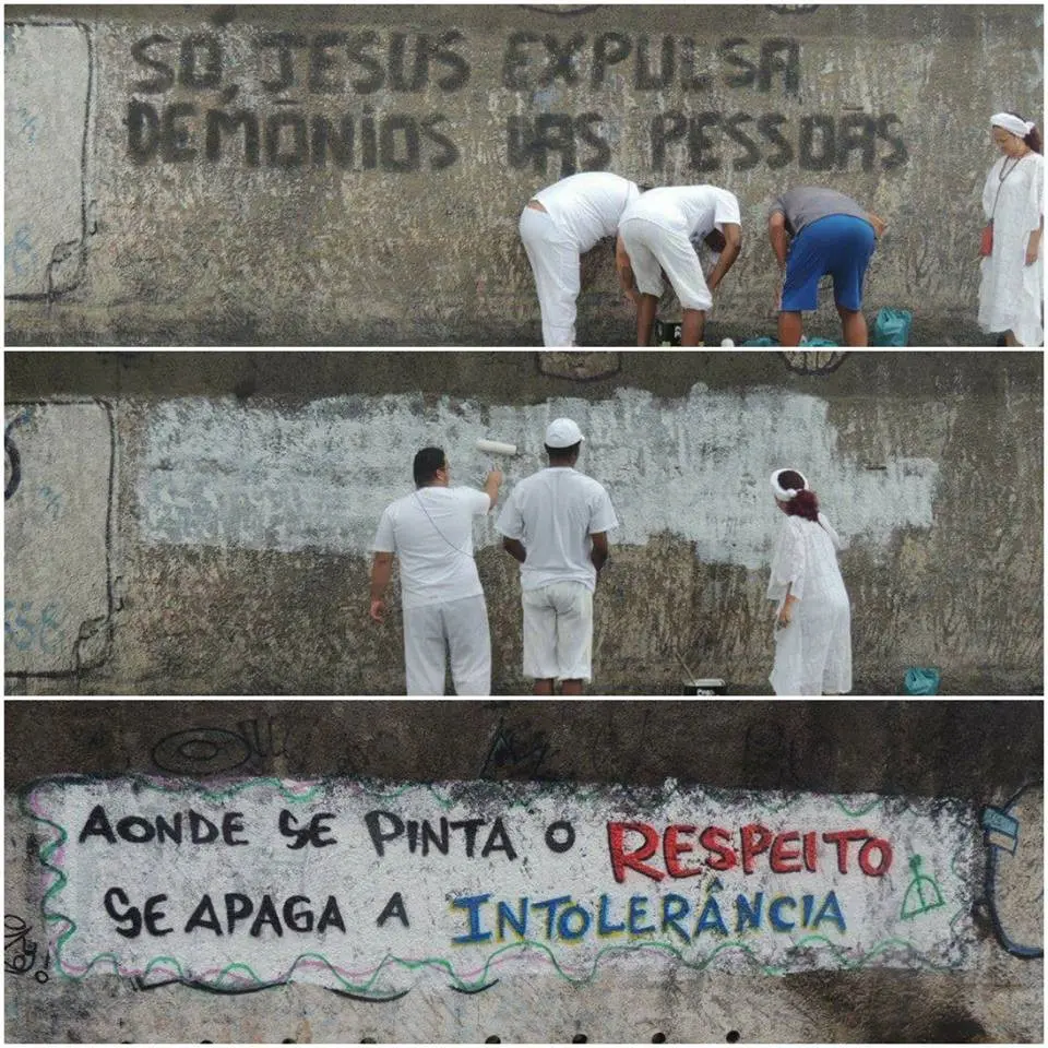 Pessoas limpam grafite de parede, substituindo mensagem antiga por nova sobre respeito e intolerância.