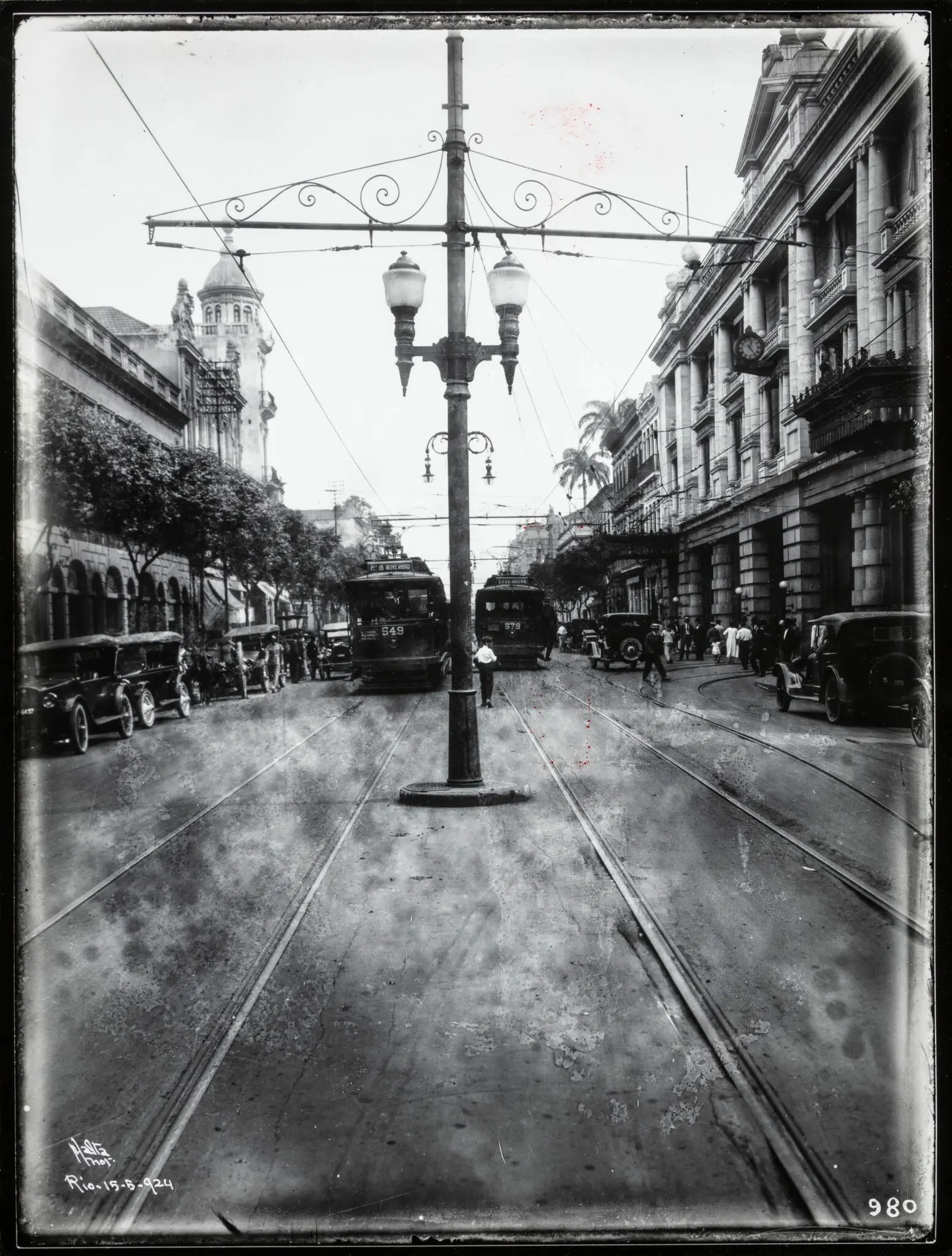 Rua urbana histórica com tráfego e pessoas.