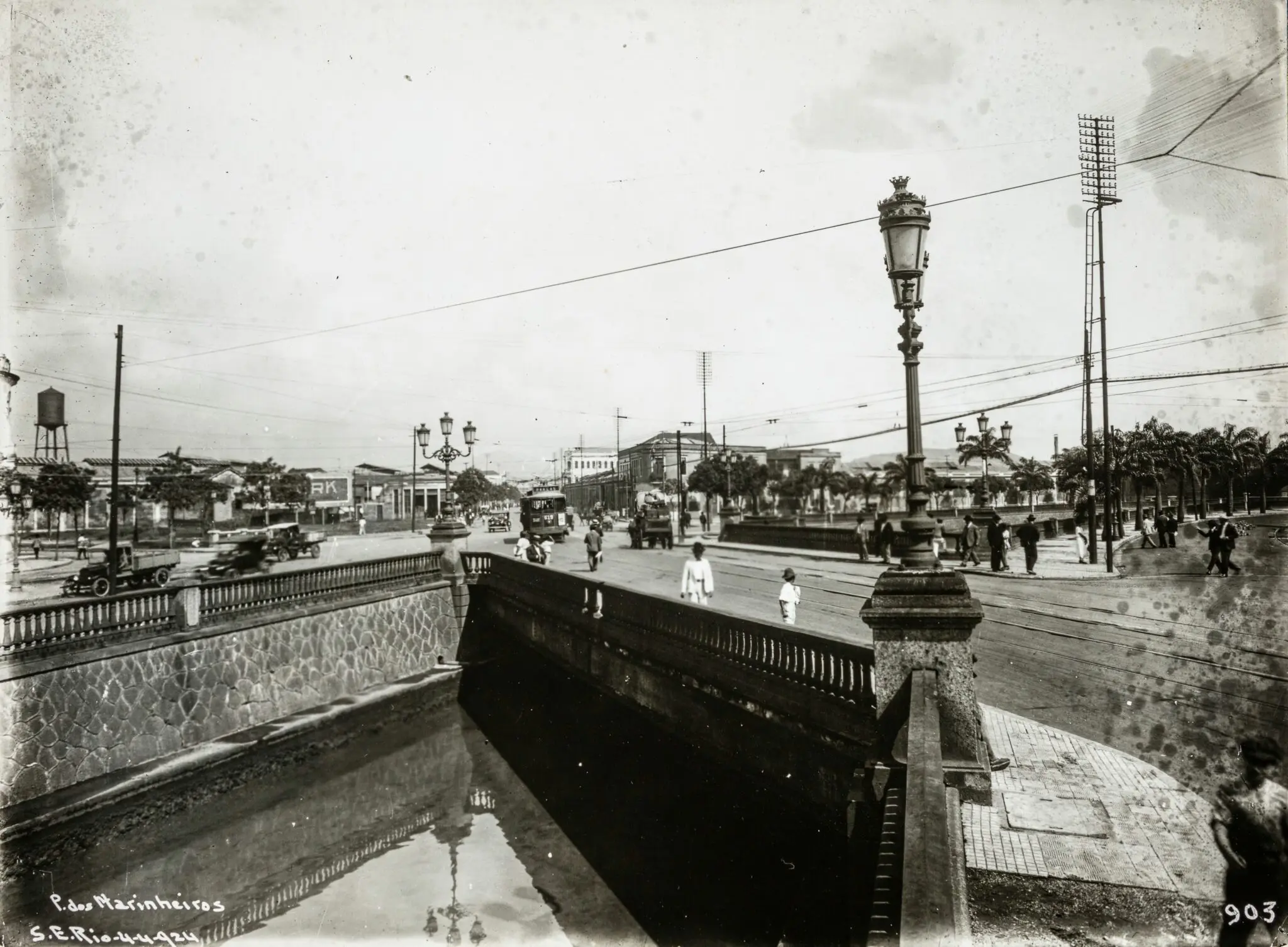 Cena urbana histórica com ponte, edifícios e pessoas caminhando.