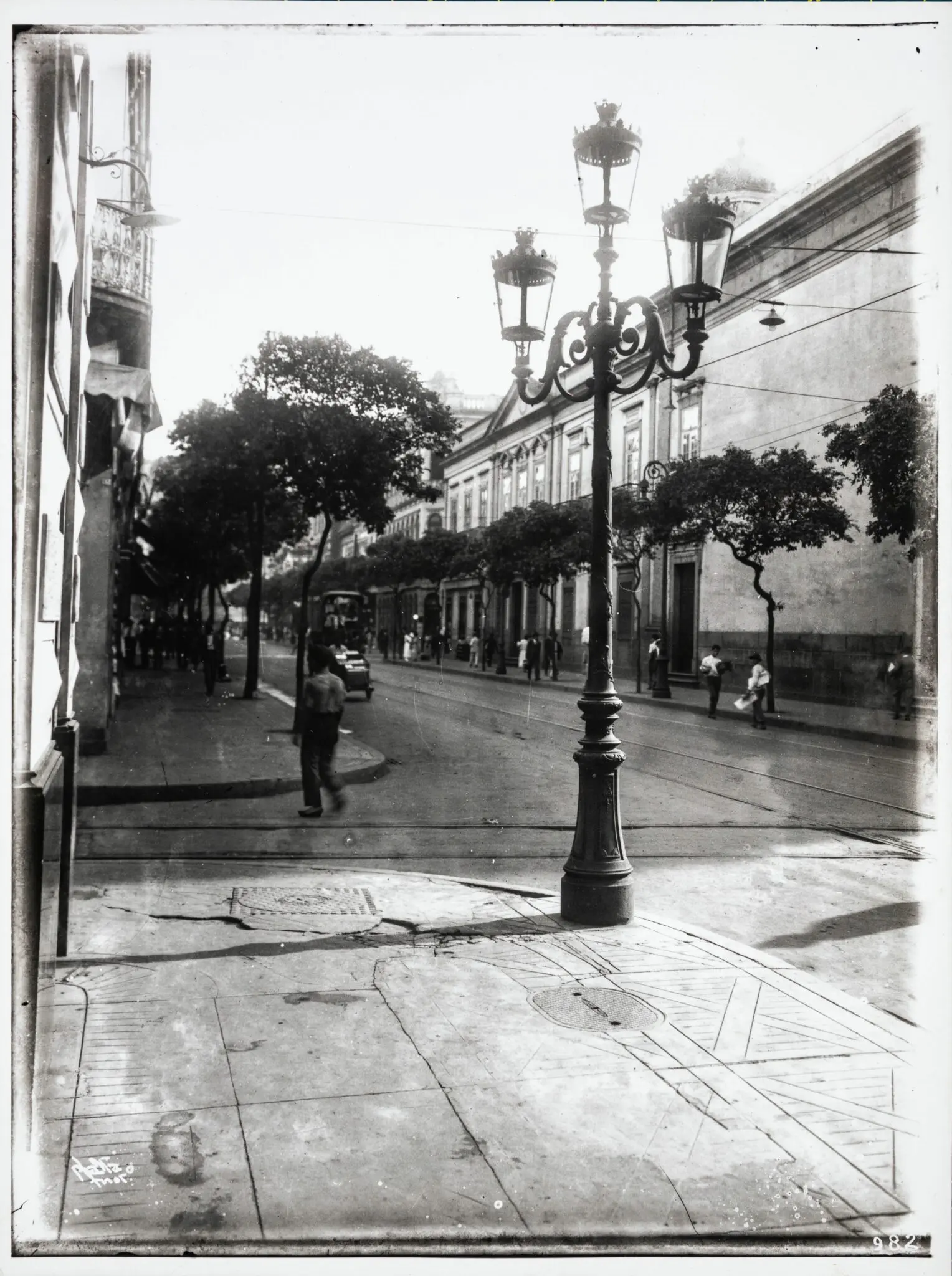 Rua urbana com edifícios e pessoas caminhando.