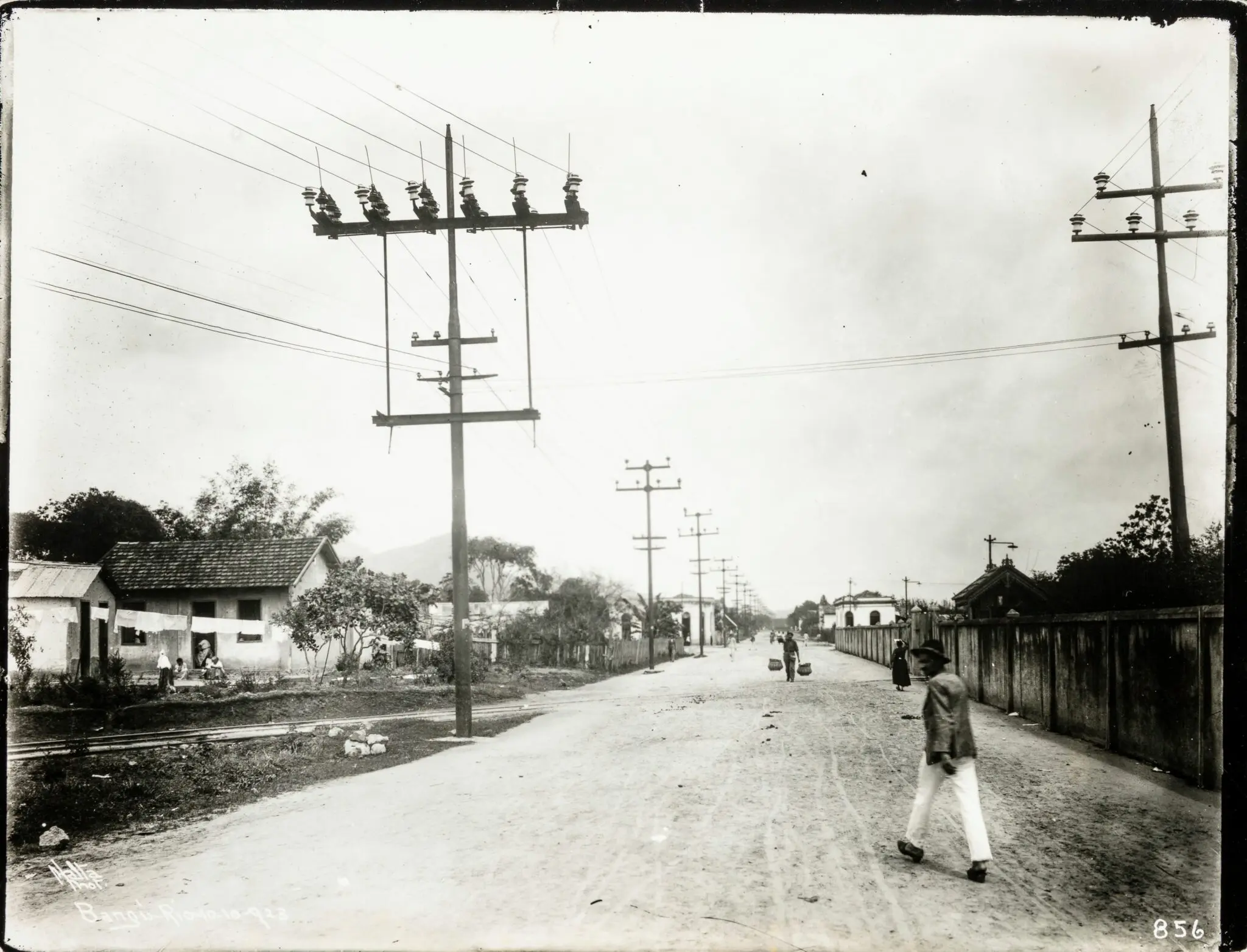 Rua antiga com pessoas caminhando e casas simples.