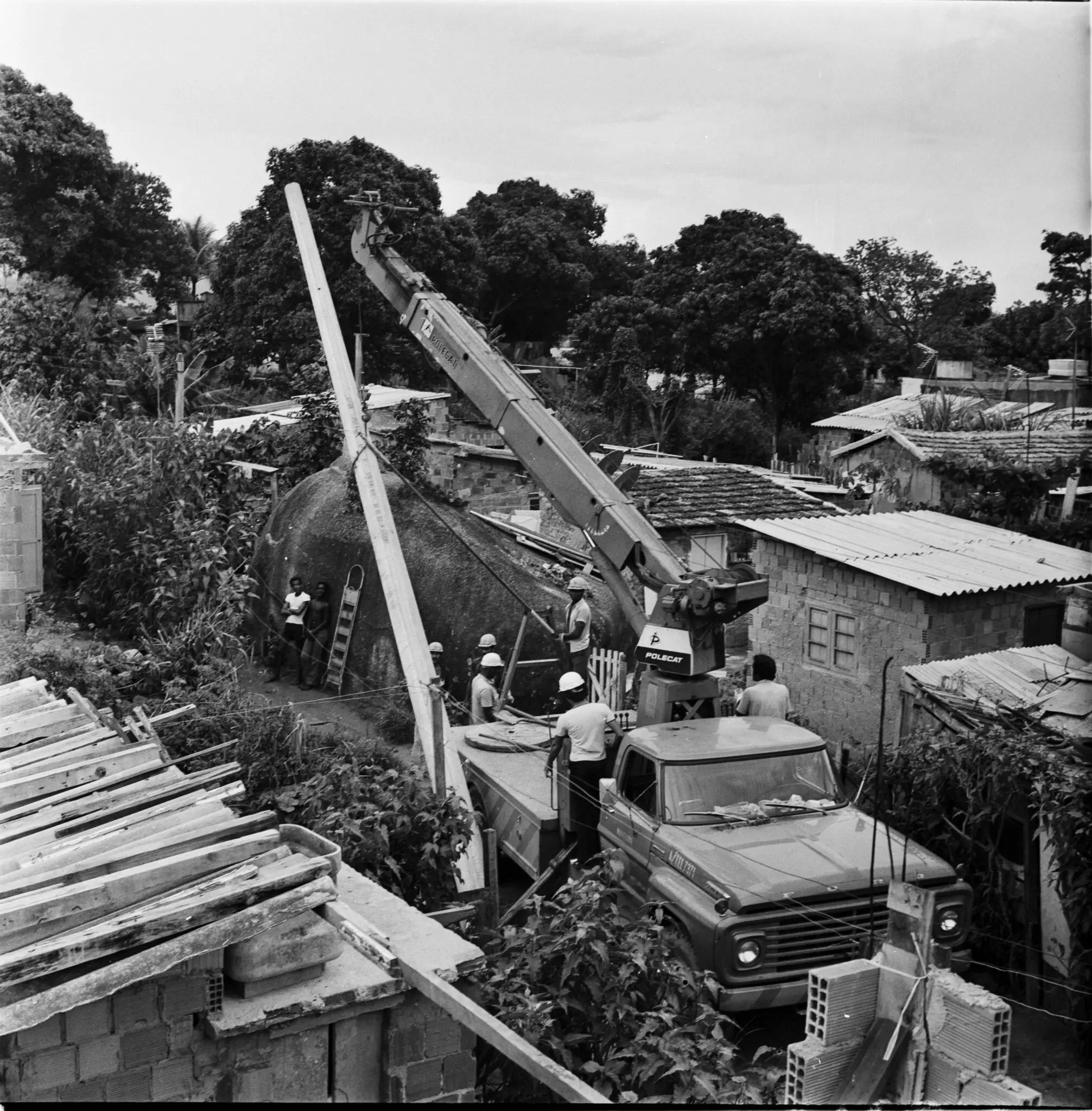 Cena de construção em bairro residencial, gravação "POLSCAT" na grua.