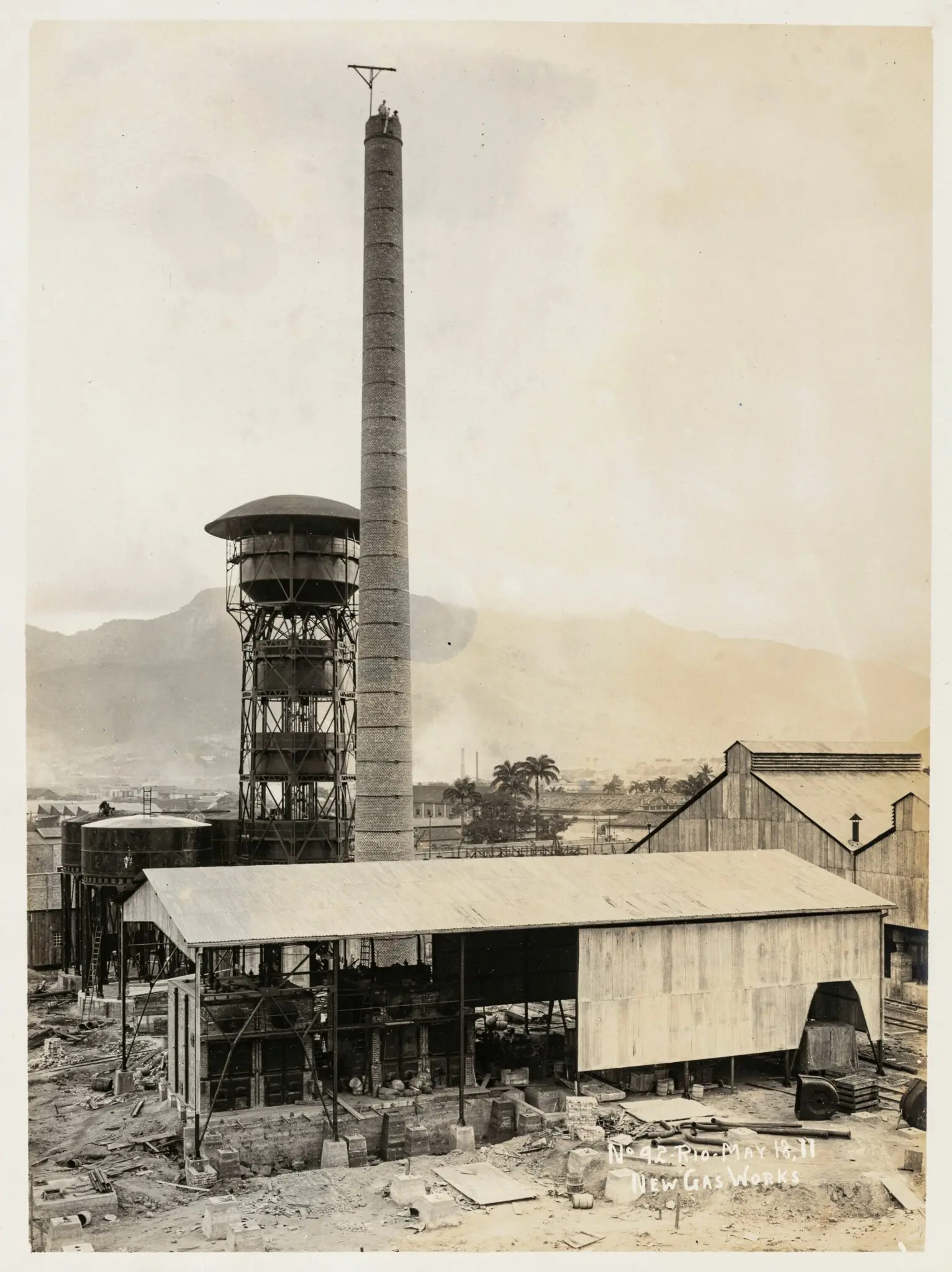 Fábrica de gás em construção, montanhas ao fundo.