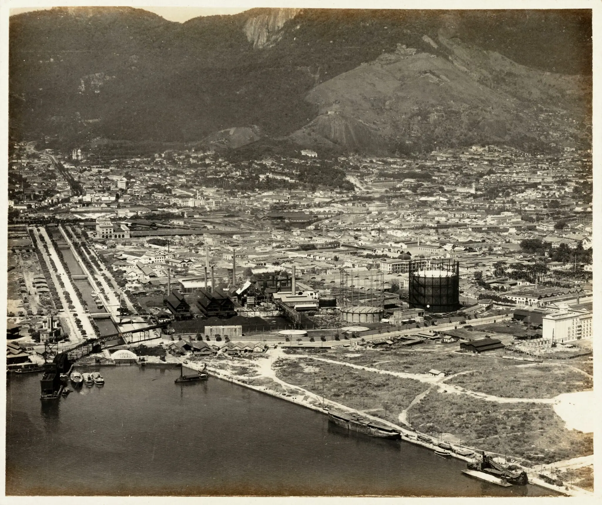 Cidade antiga com montanhas, rio e indústria.