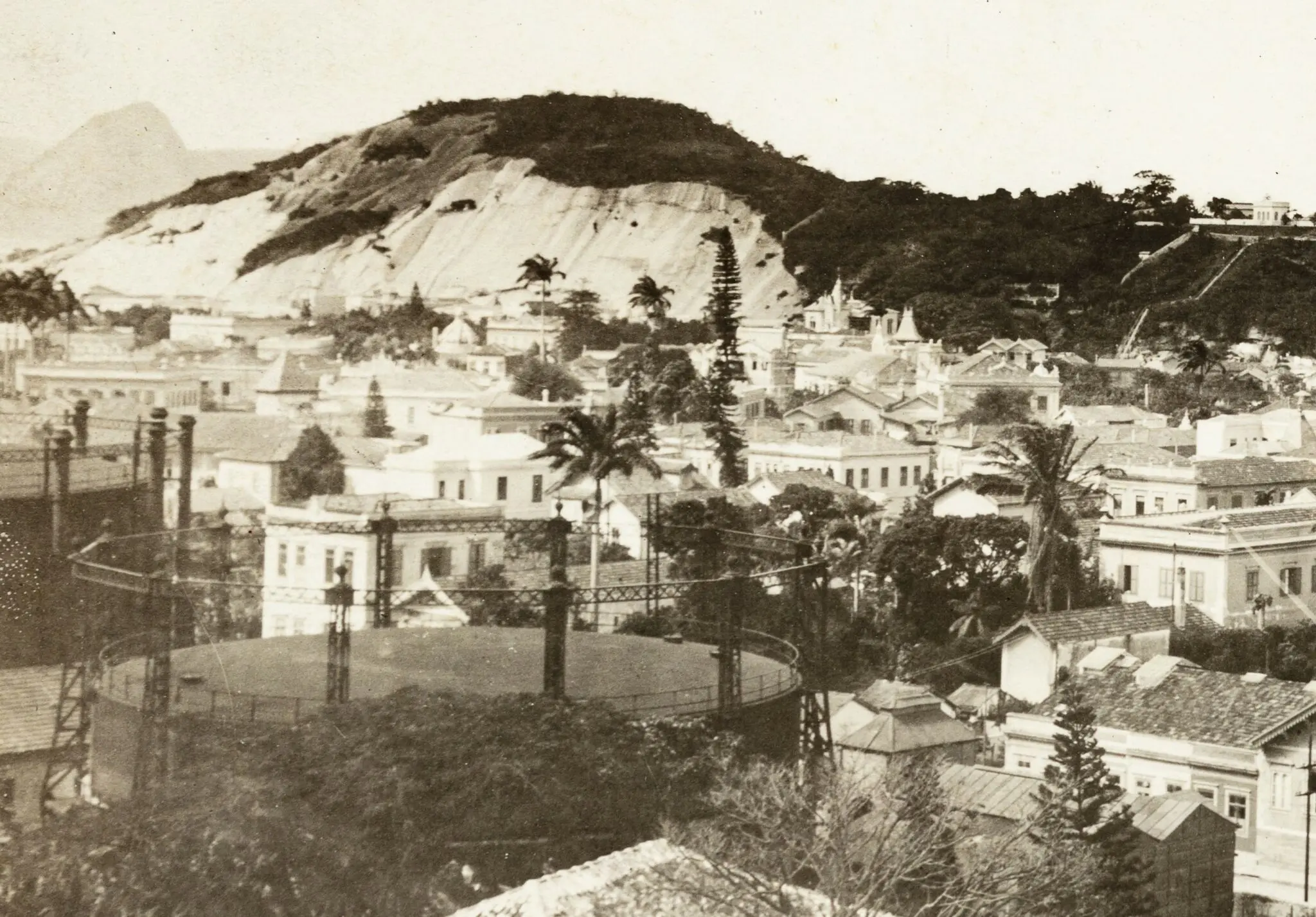 Cidade antiga com casarios, subestação elétrica e montanha ao fundo.