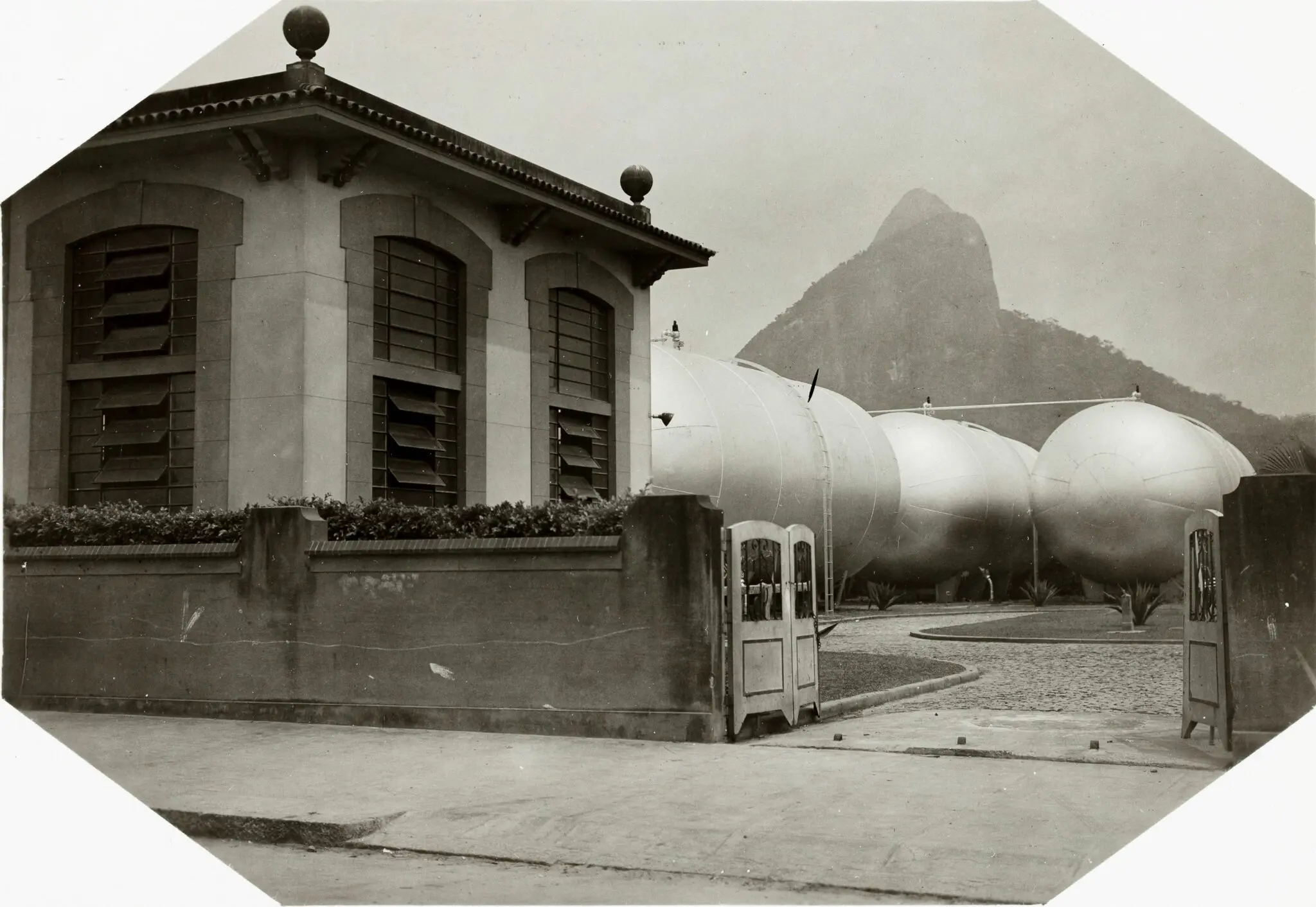Subestação elétrica com tanques cilíndricos e montanha rochosa ao fundo.