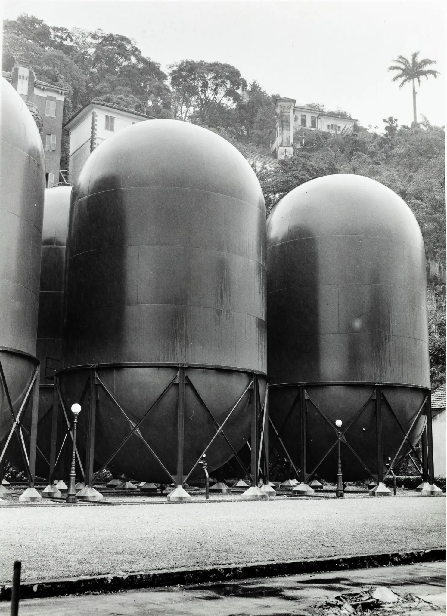 Tanques metálicos em parque, casa ao fundo.
