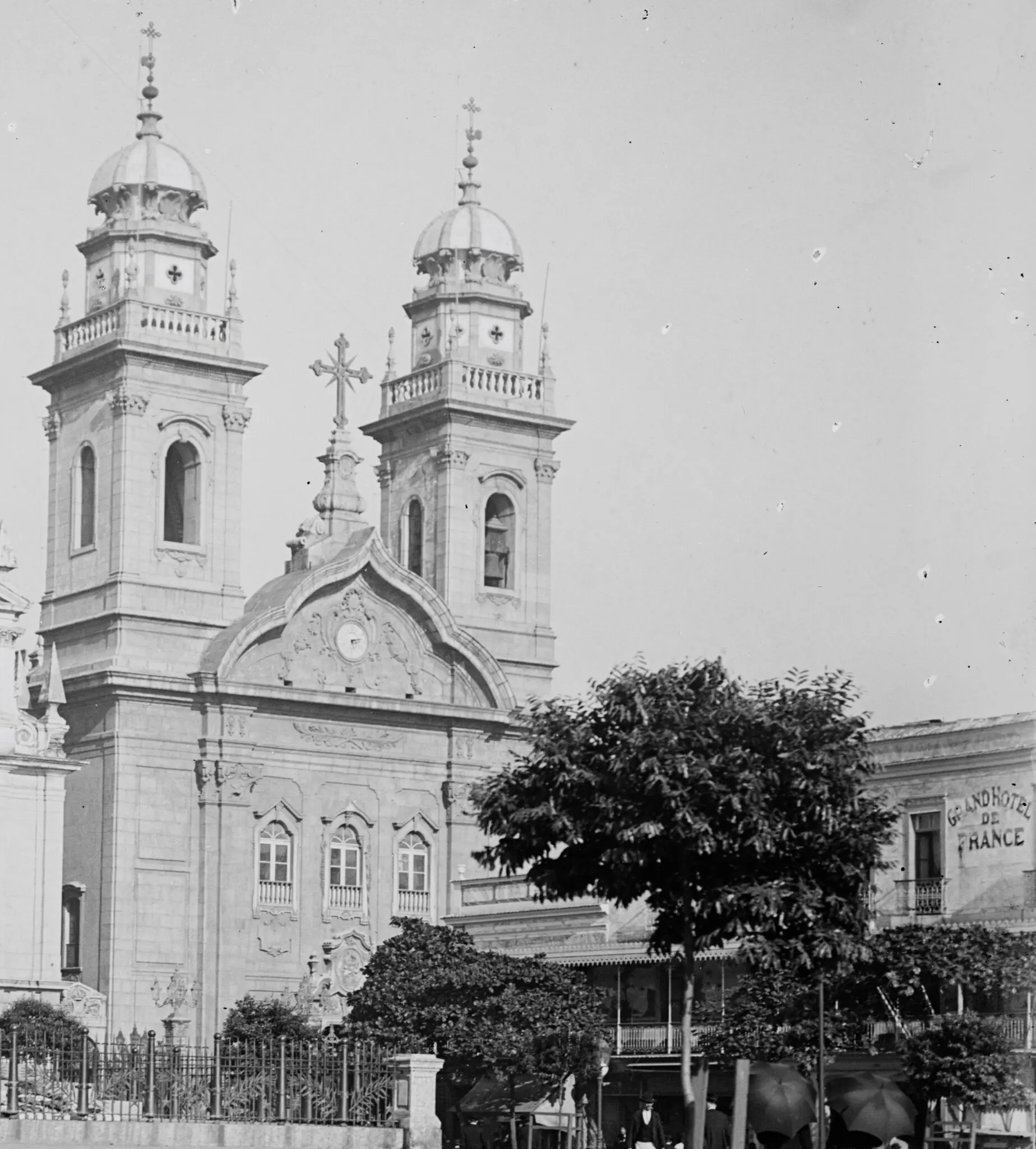 Igreja histórica com torres e árvore verde ao fundo.