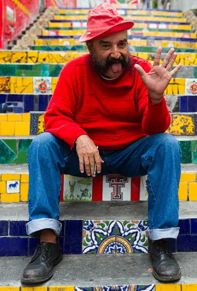 Homem sorridente em escadaria colorida.