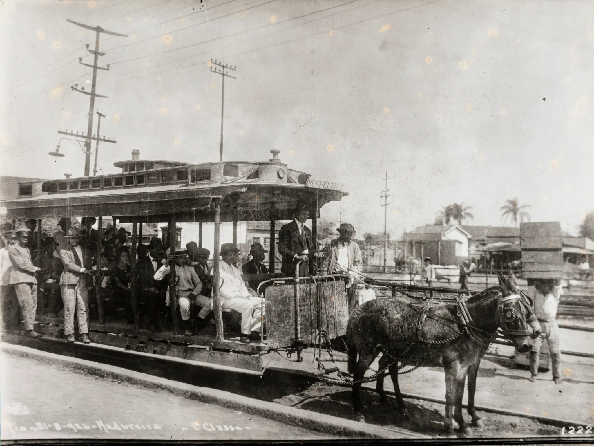 Bonde histórico em preto e branco, com pessoas e burro.