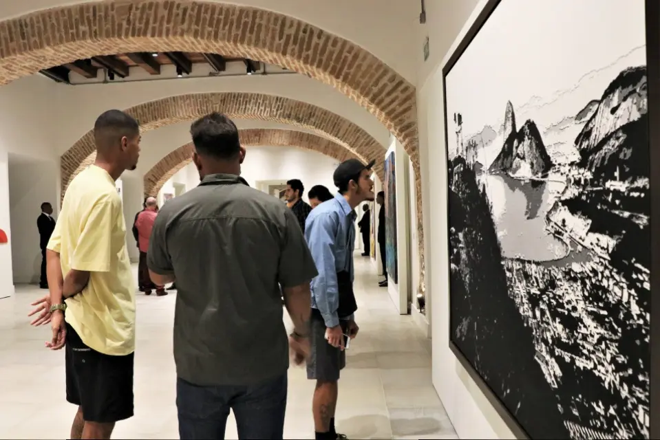 Galeria de arte com arco de tijolo e obra preto-branco de paisagem.