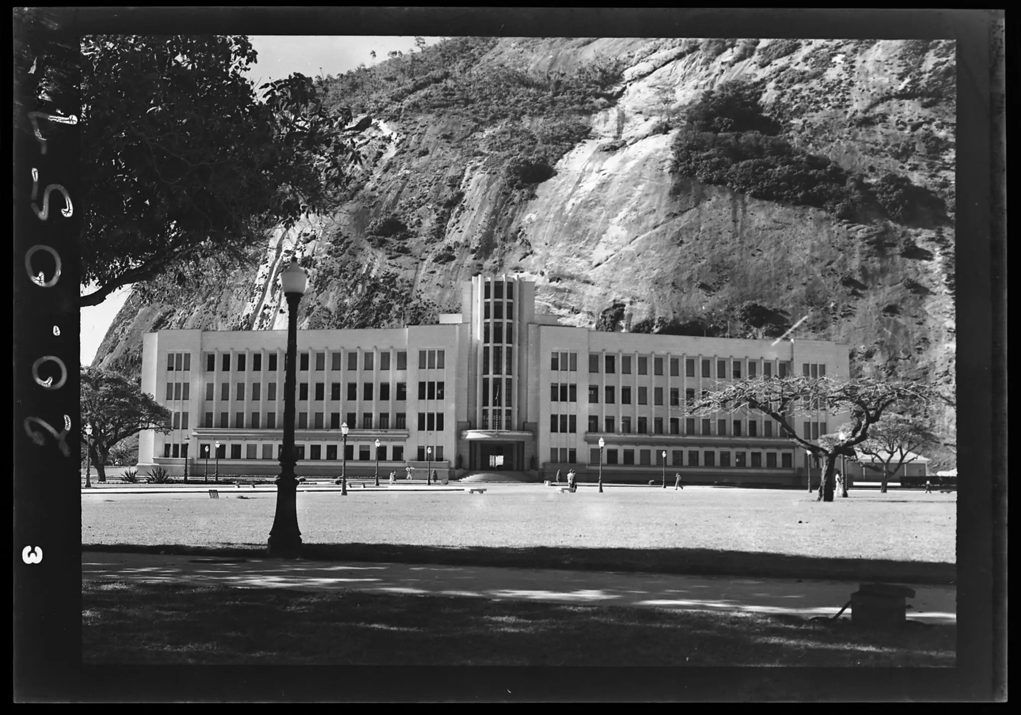 Edifício moderno em frente à rocha escarpada, com árvores verdes.